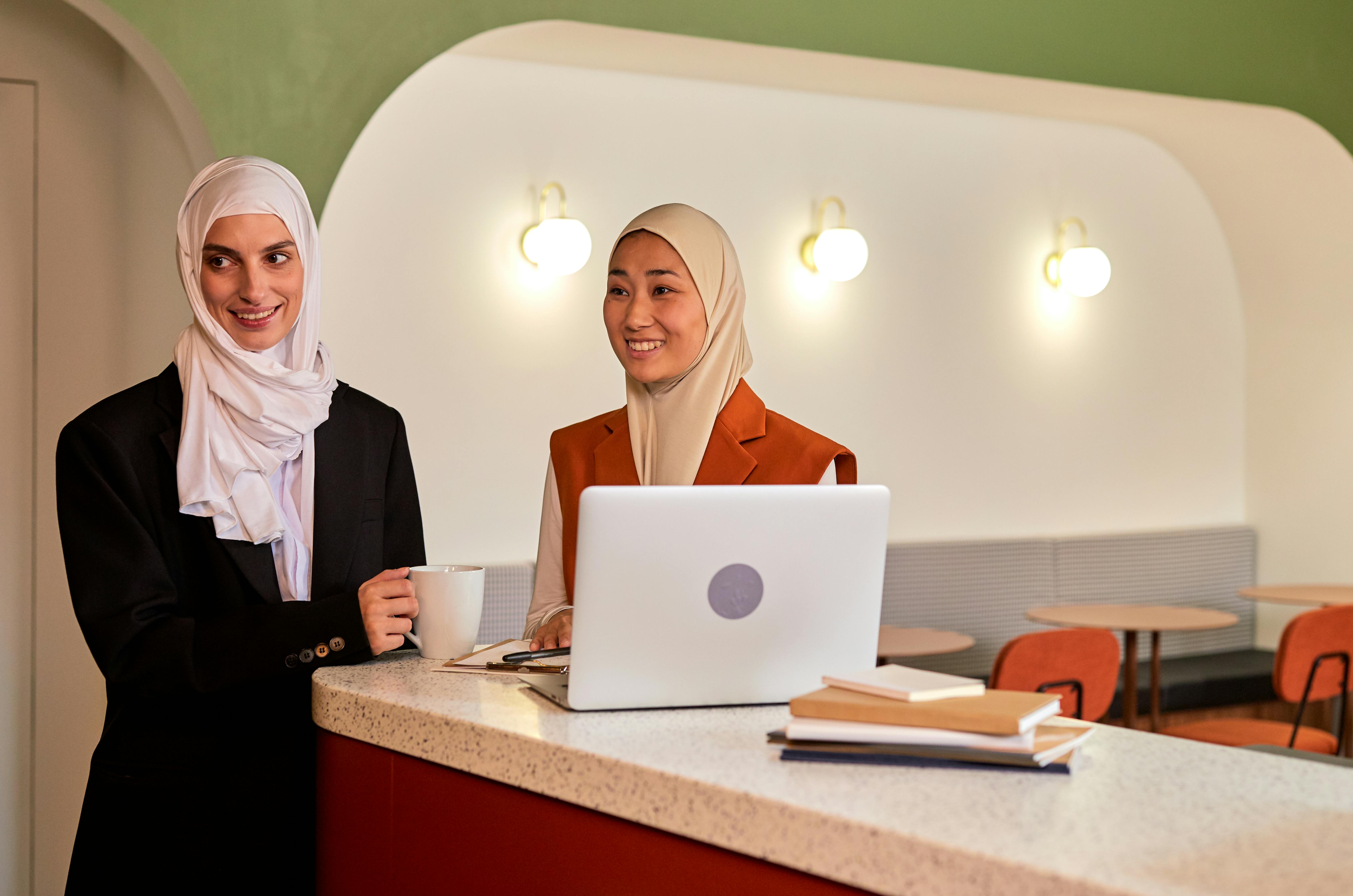 Two Females Smiling and Wearing Hijab in Modern Office