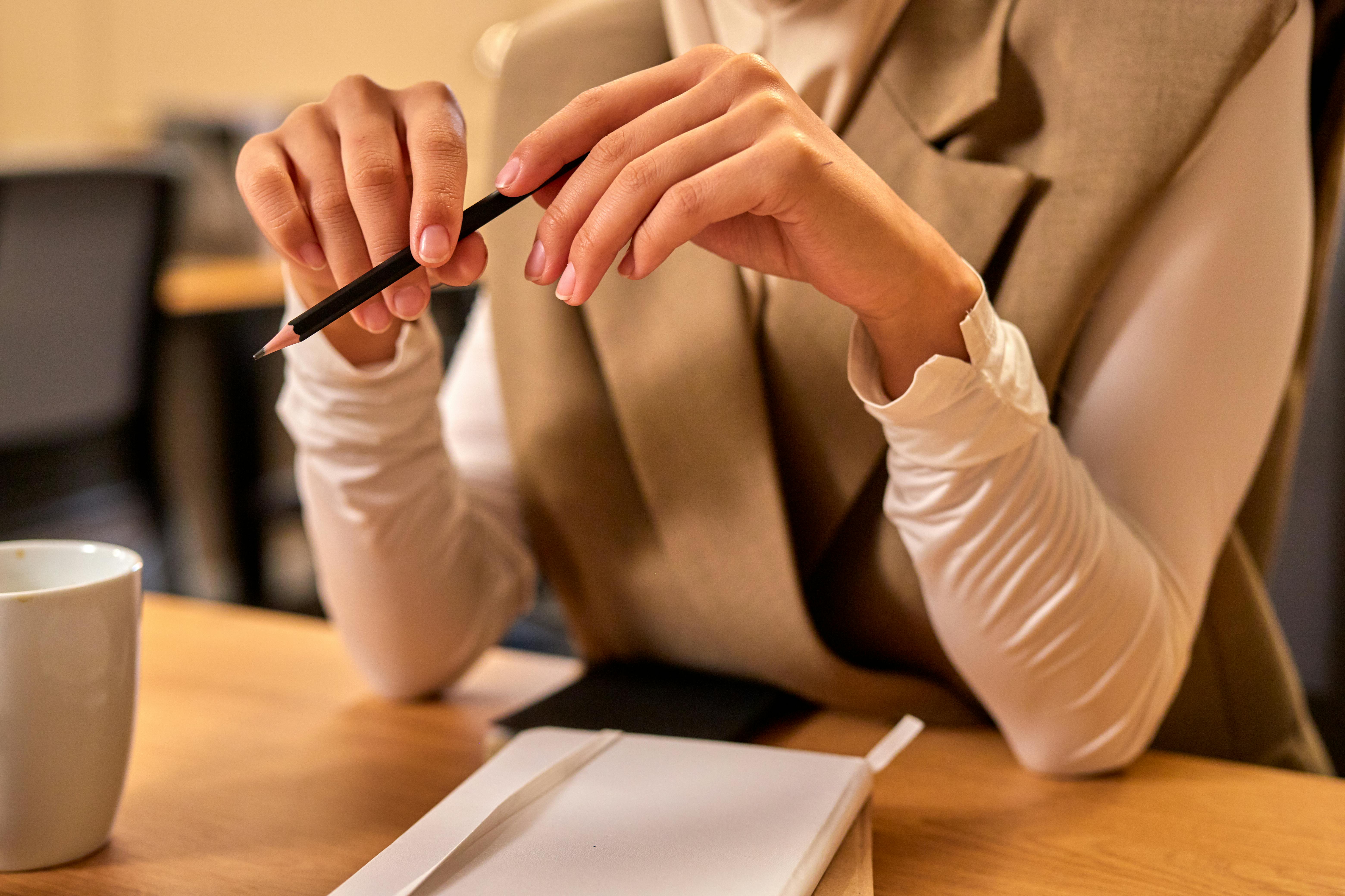 Female Hands Holding Pencil over Office Desk