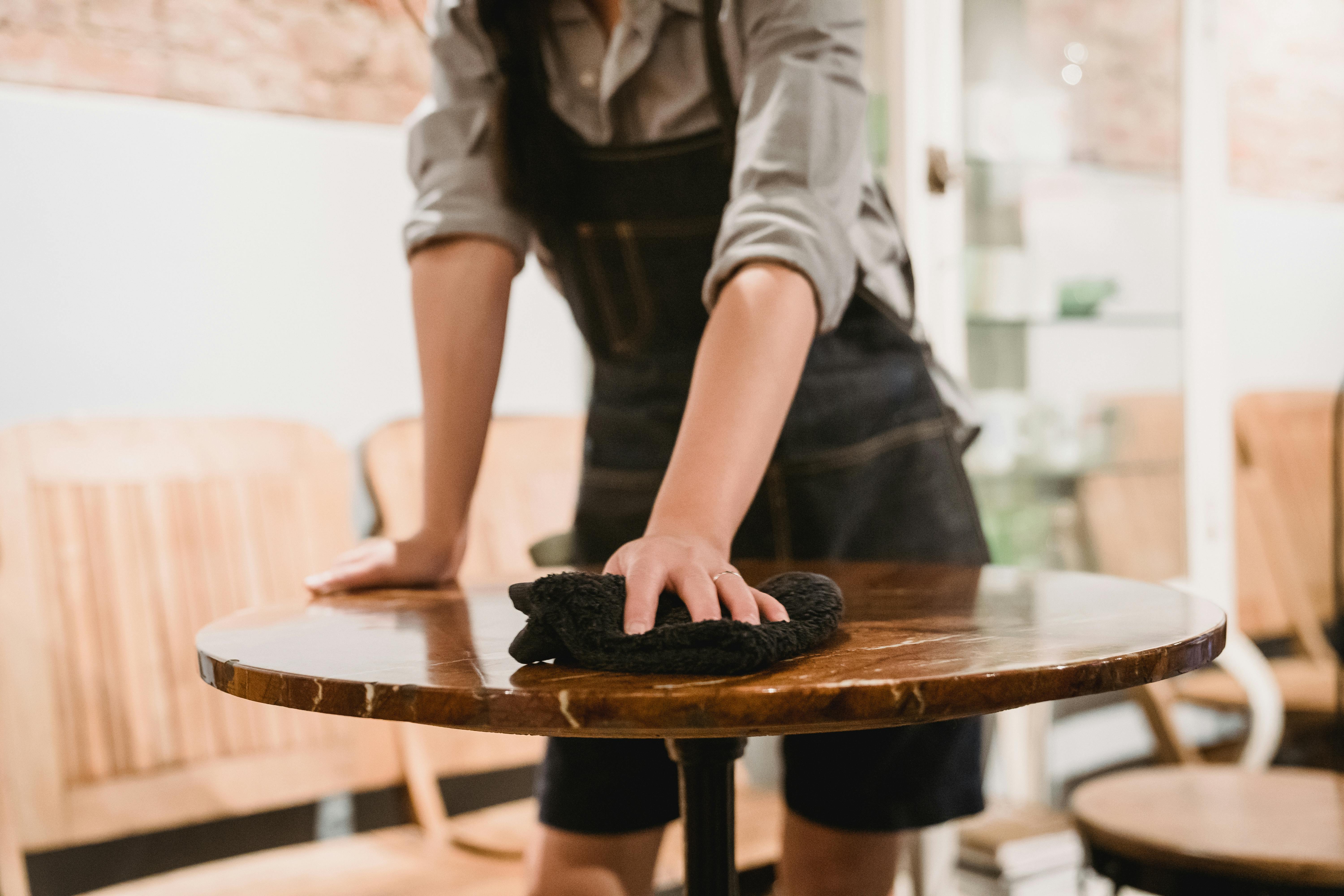 Person Cleaning Table in Cafe