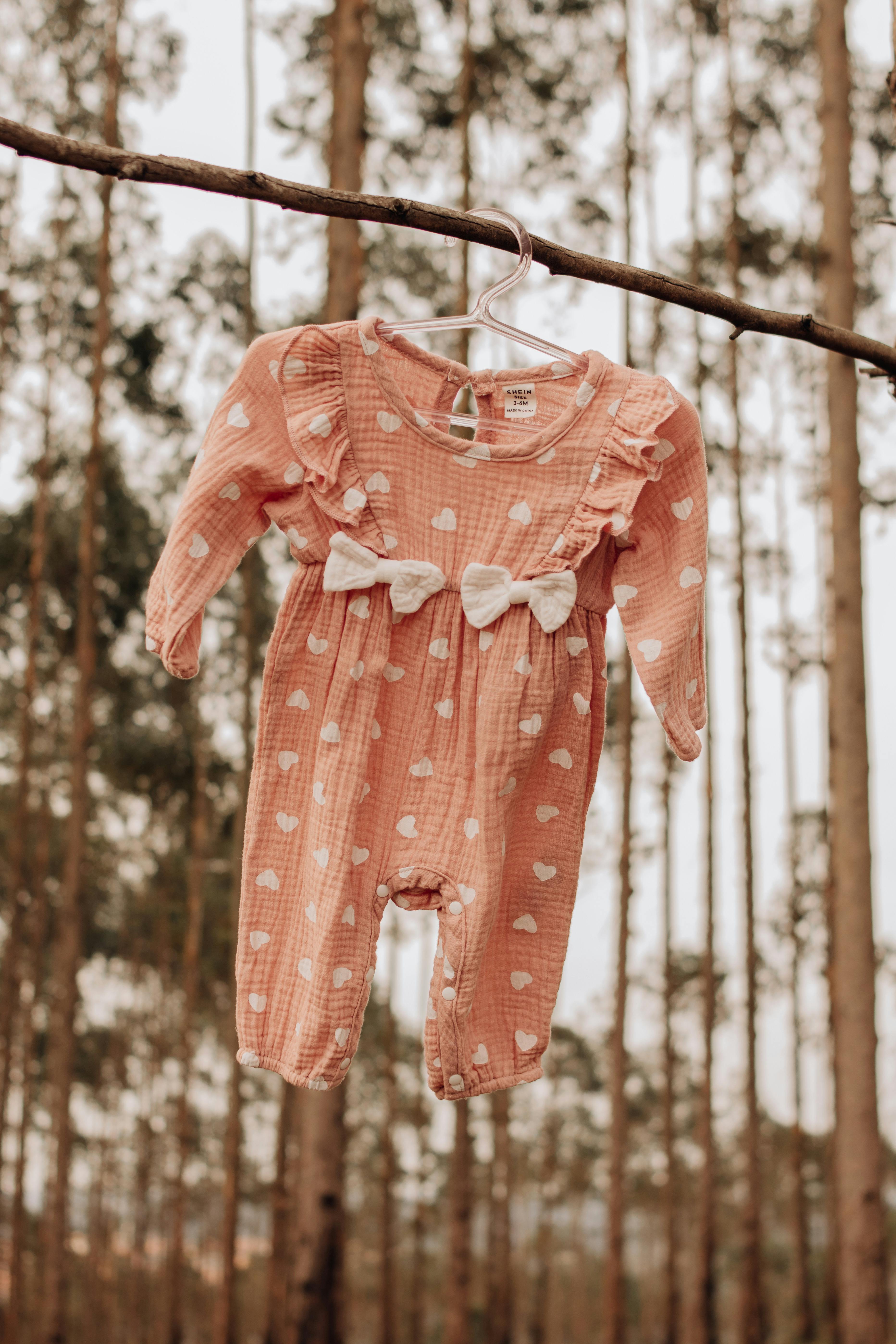 Adorable Pink Baby Romper Hanging in Forest