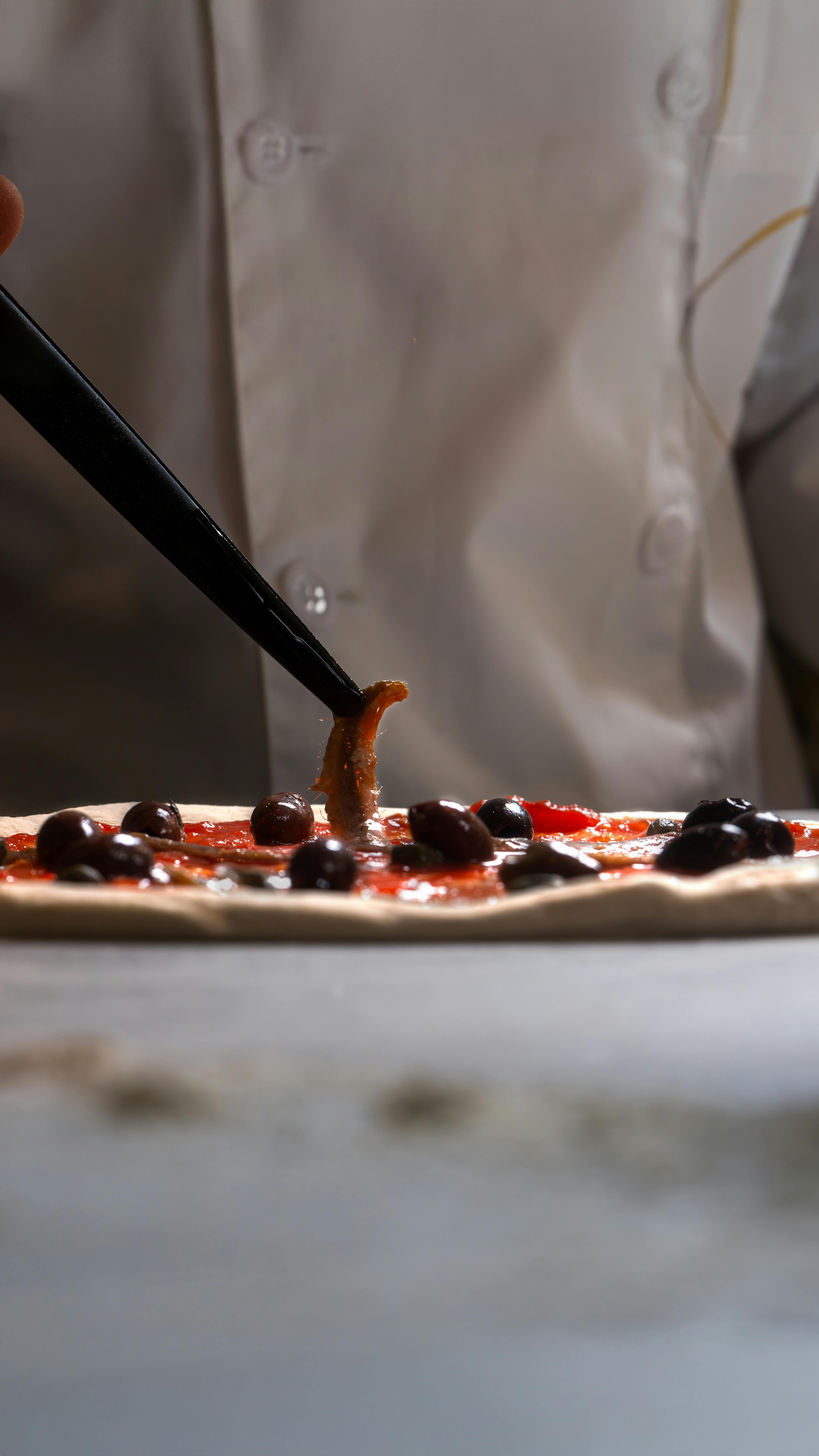 Chef Preparing Artisan Pizza with Olives