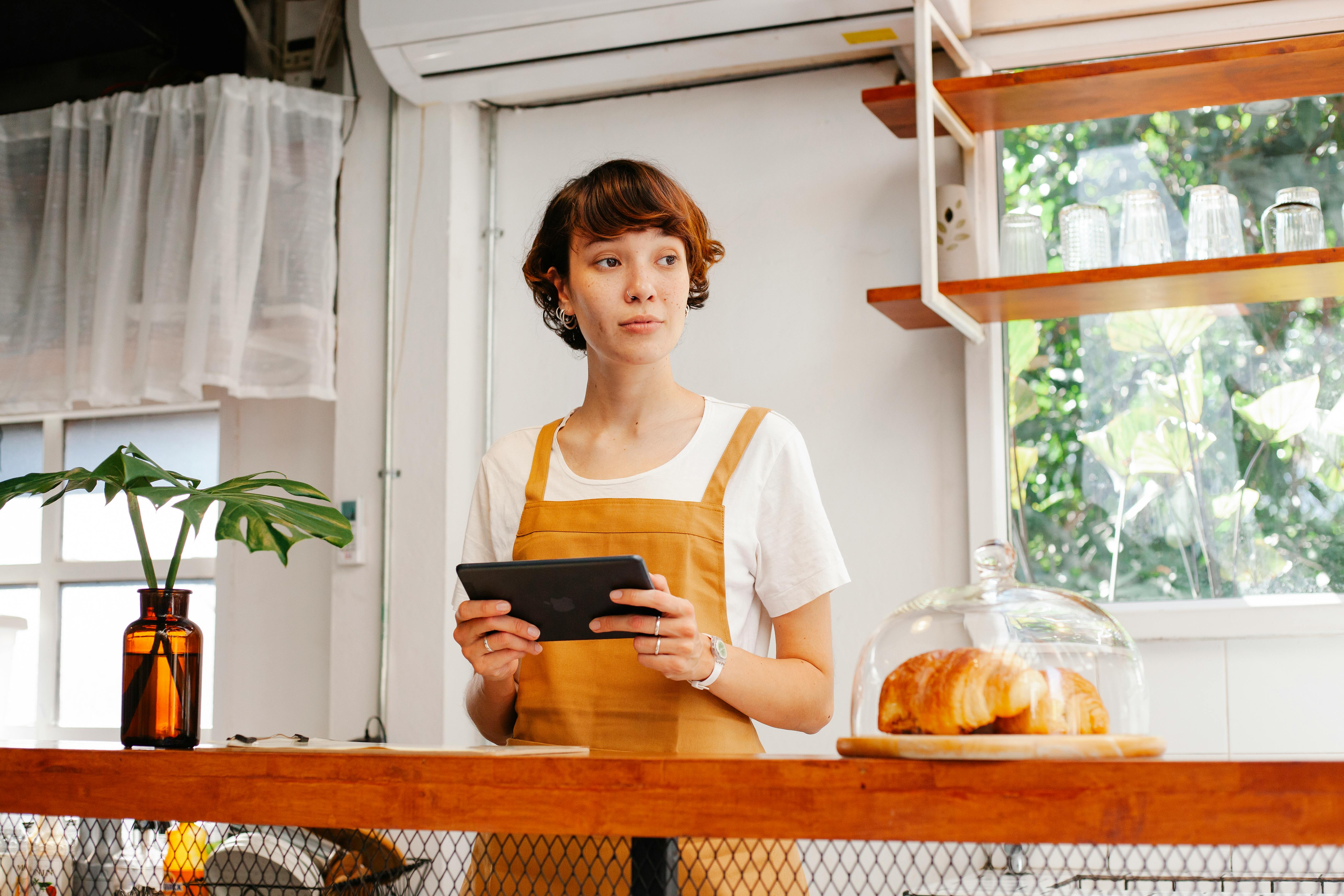 Baker with tablet at counter in cafe