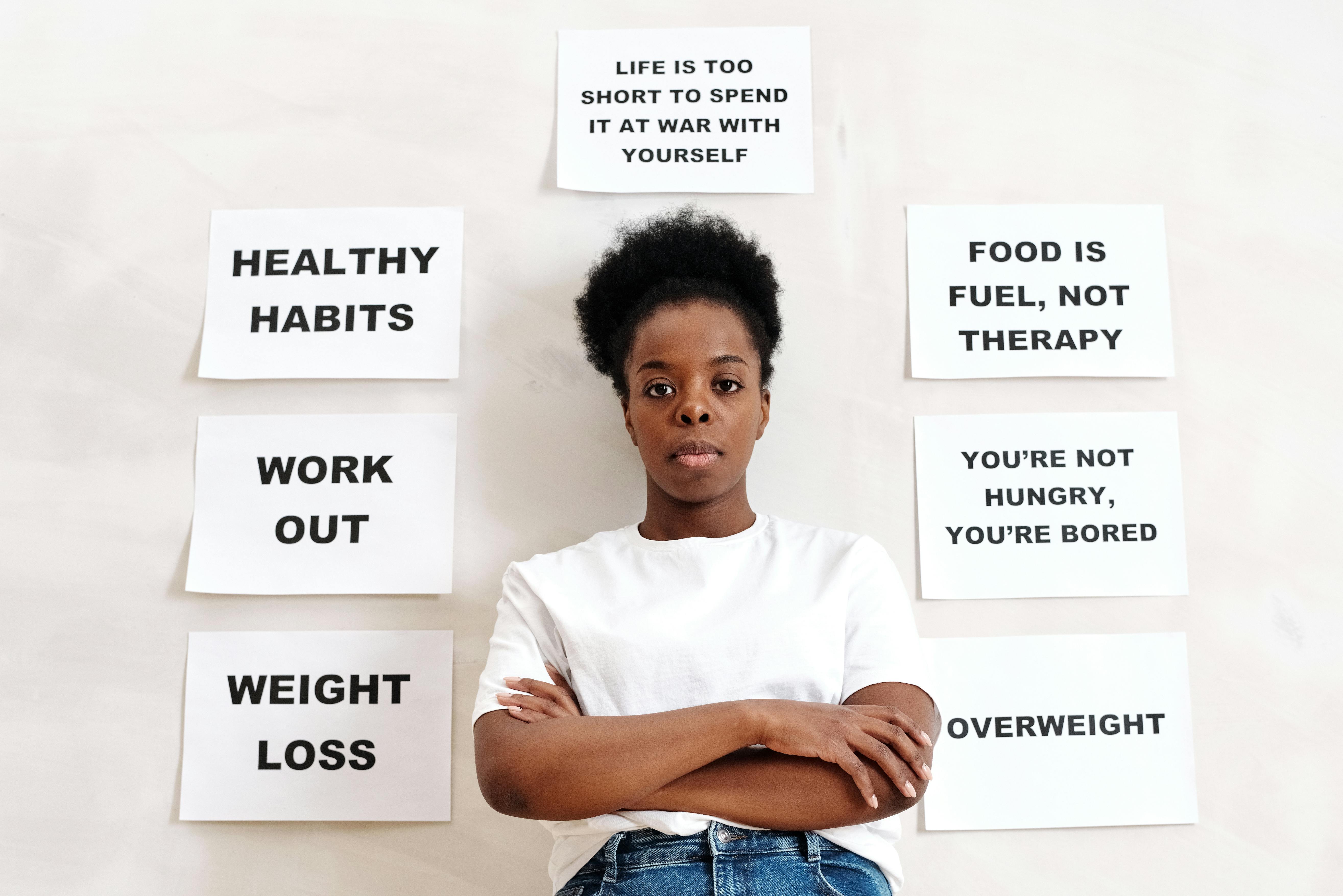Woman in White Crew Neck T-shirt Standing Beside a Wall with Slogans
