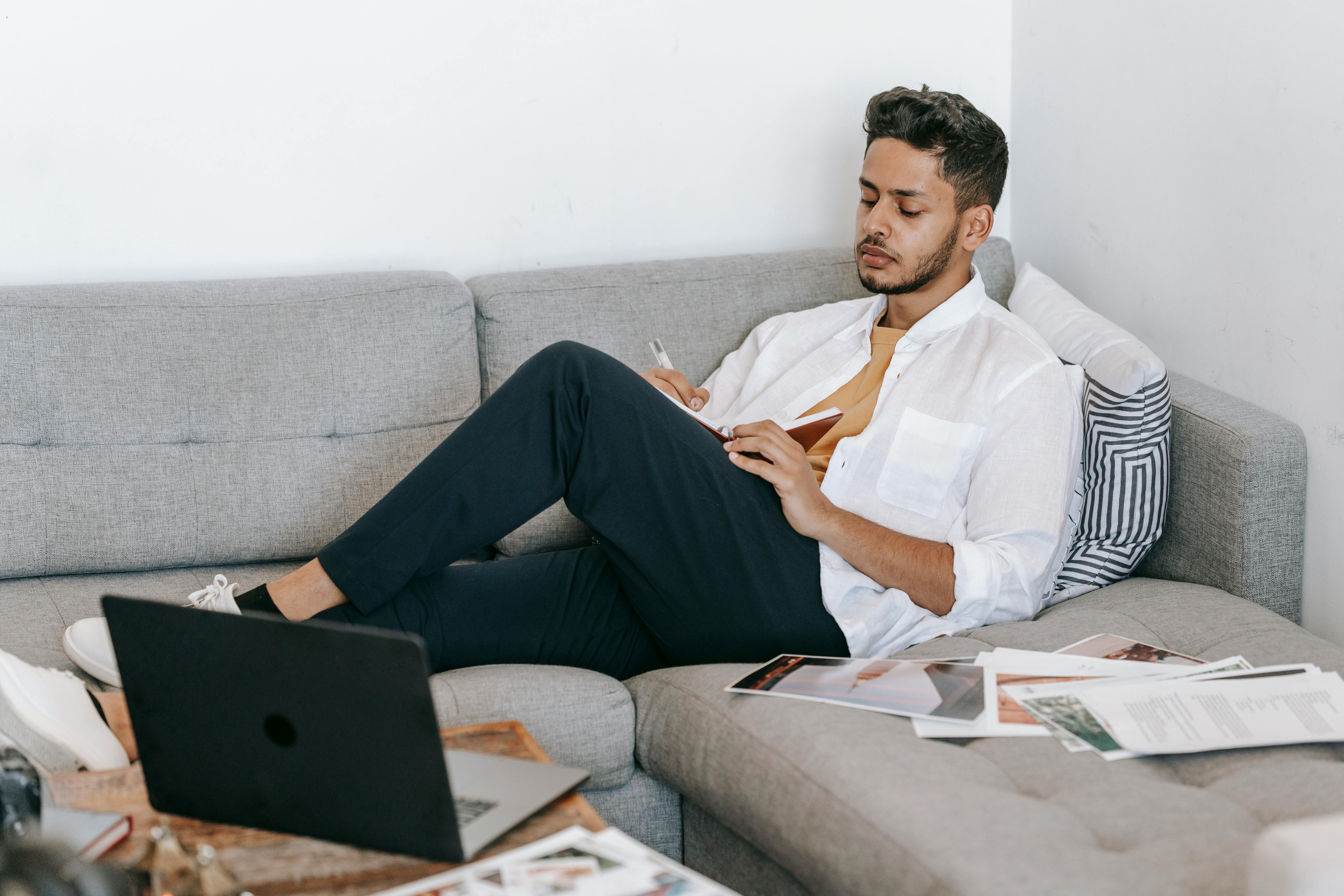 Man taking notes in notebook near laptop