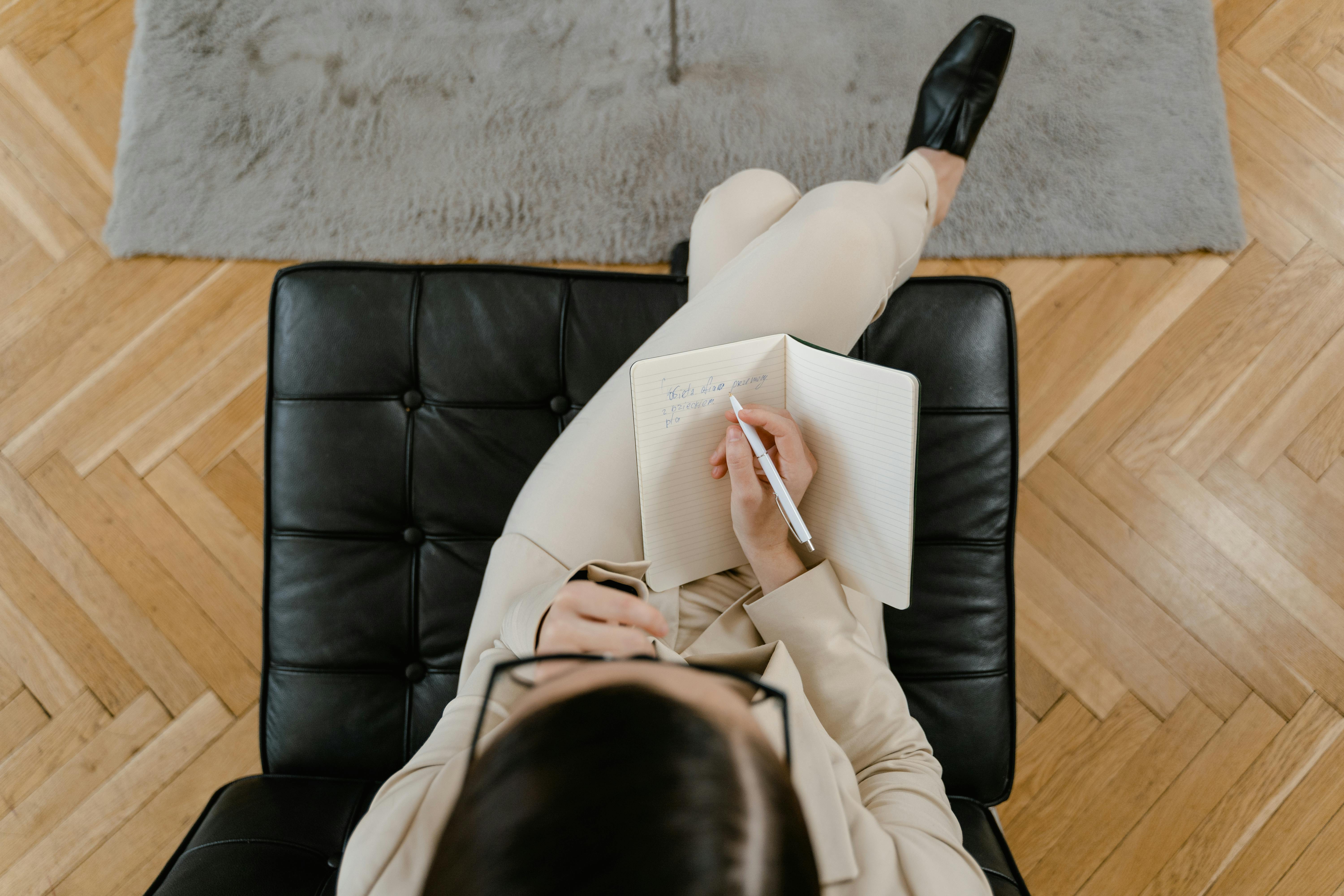 Overhead Shot of a Woman in Beige Long Sleeves Writing on a Notebook