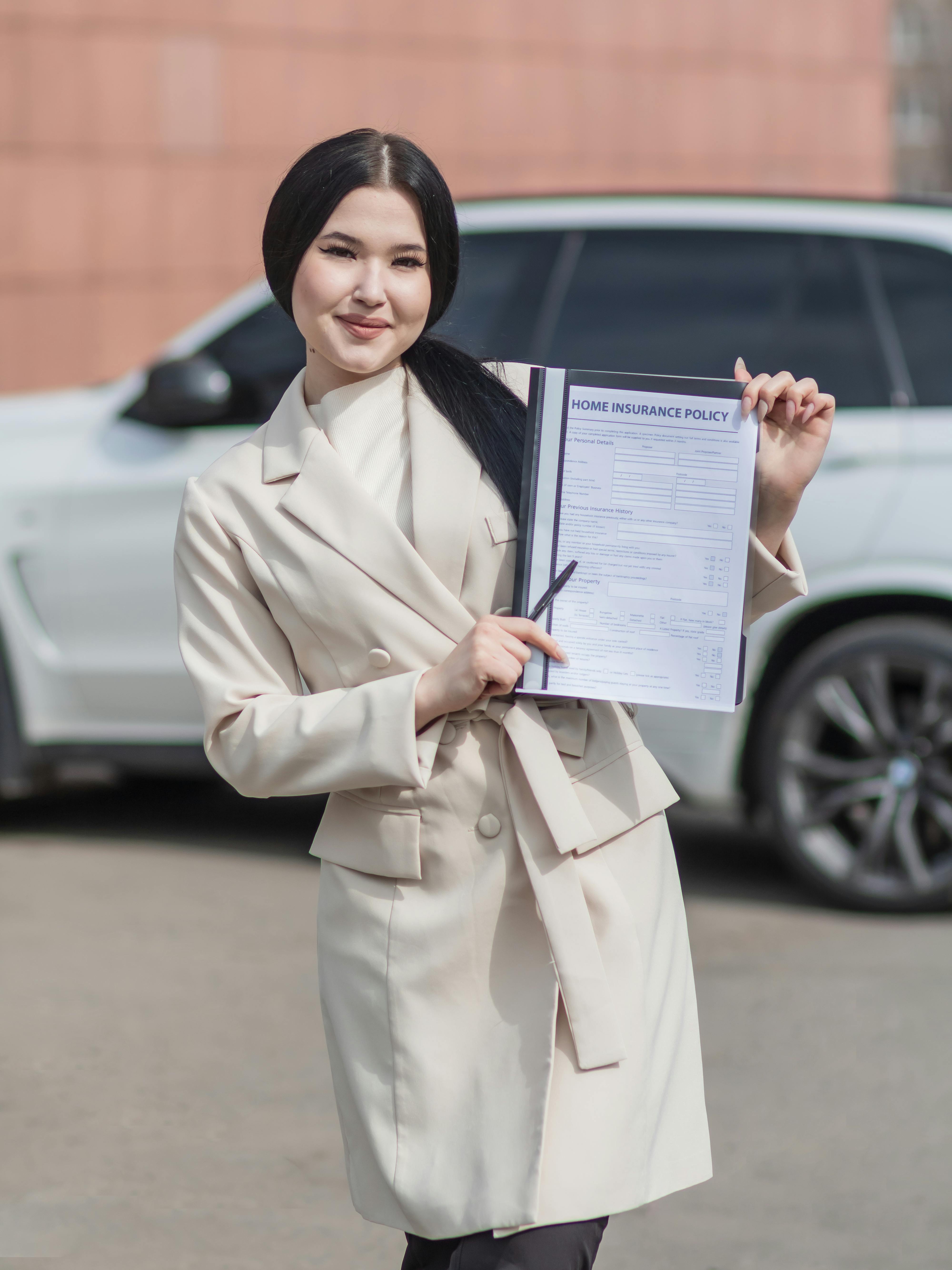 A Woman in Beige Trench Coat Holding an Insurance Policy while Standing on the Street