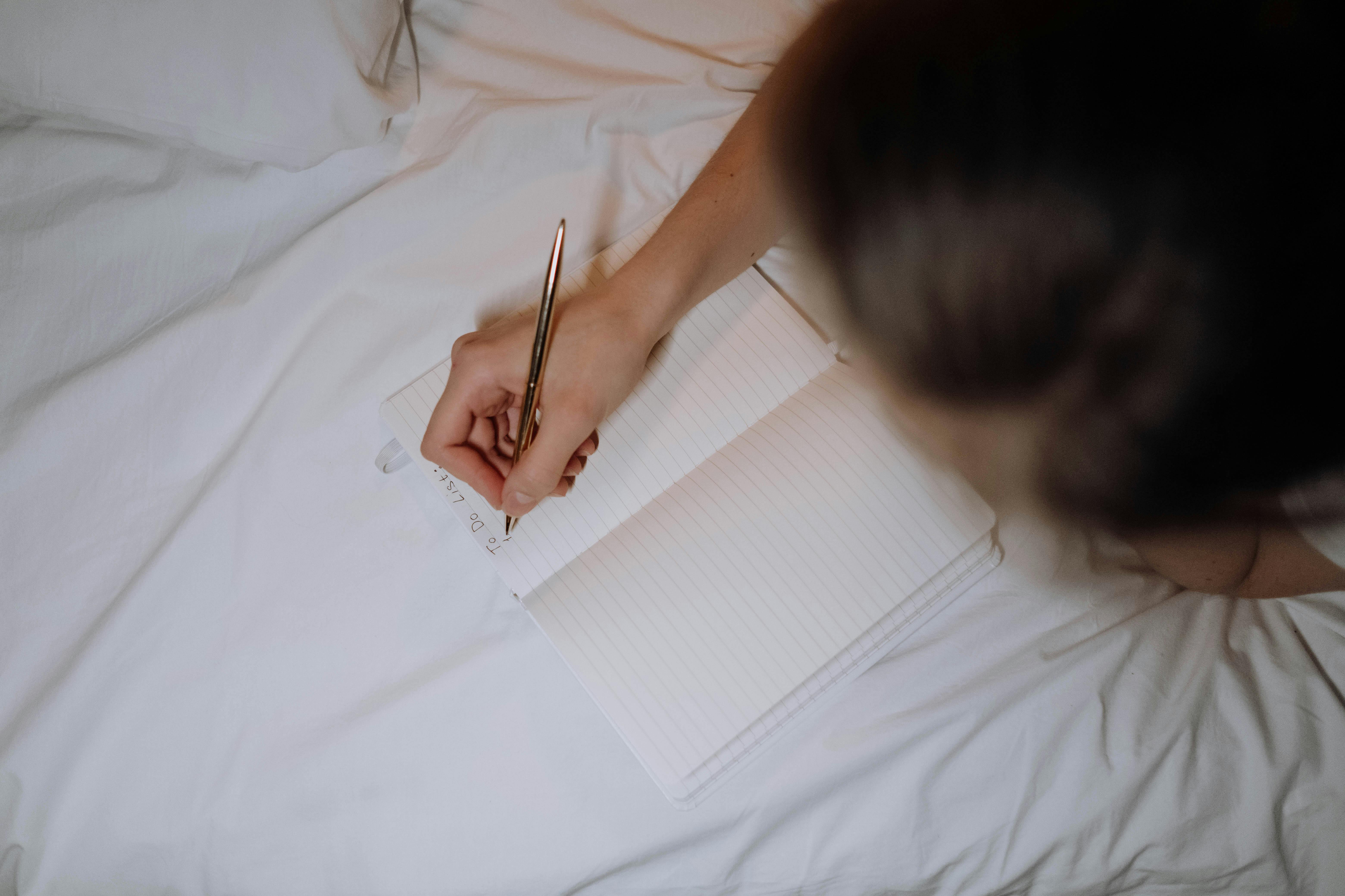 A Person Writing on a Notebook
