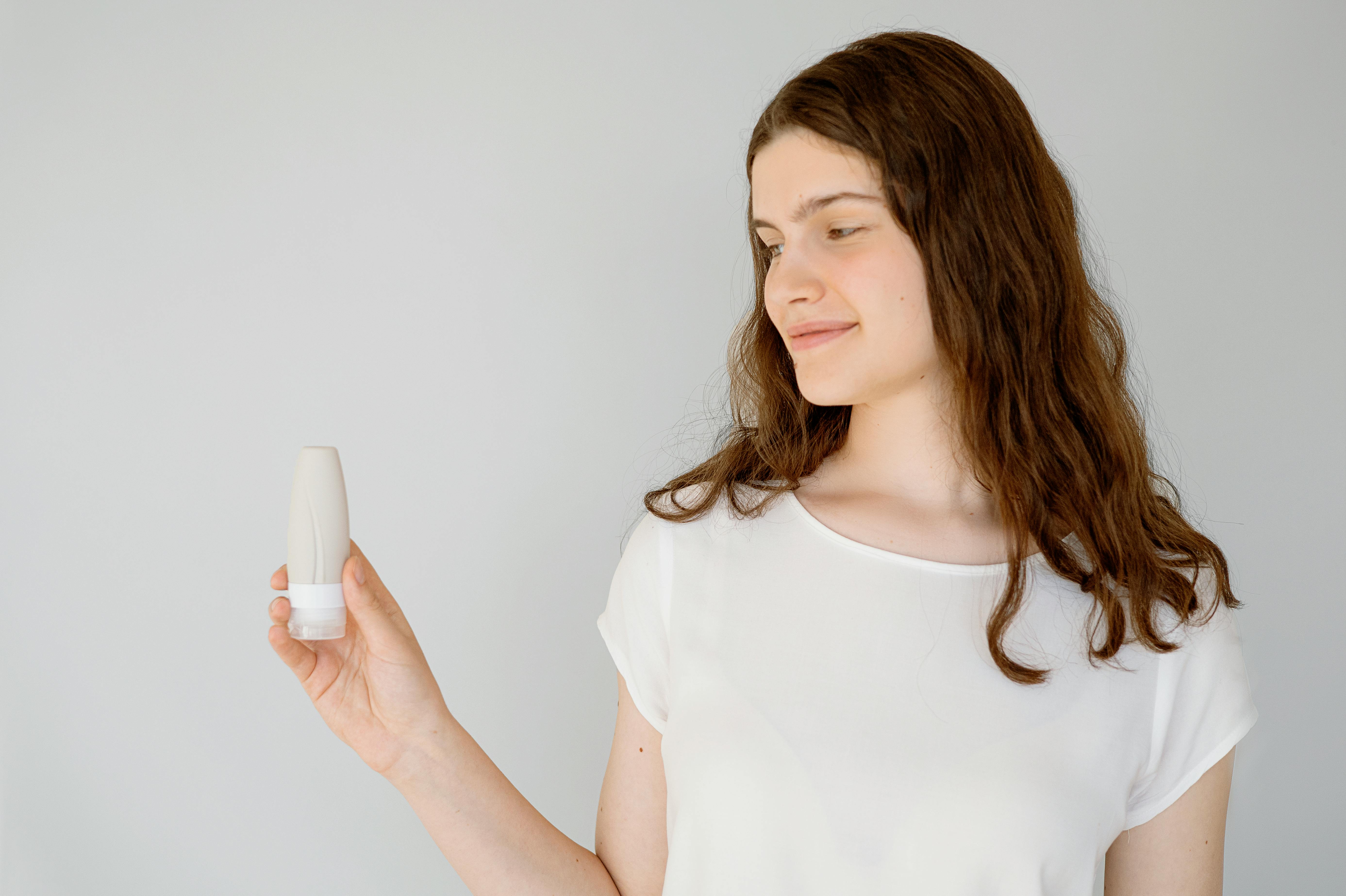 Woman in White Blouse Holding a Travel Bottle