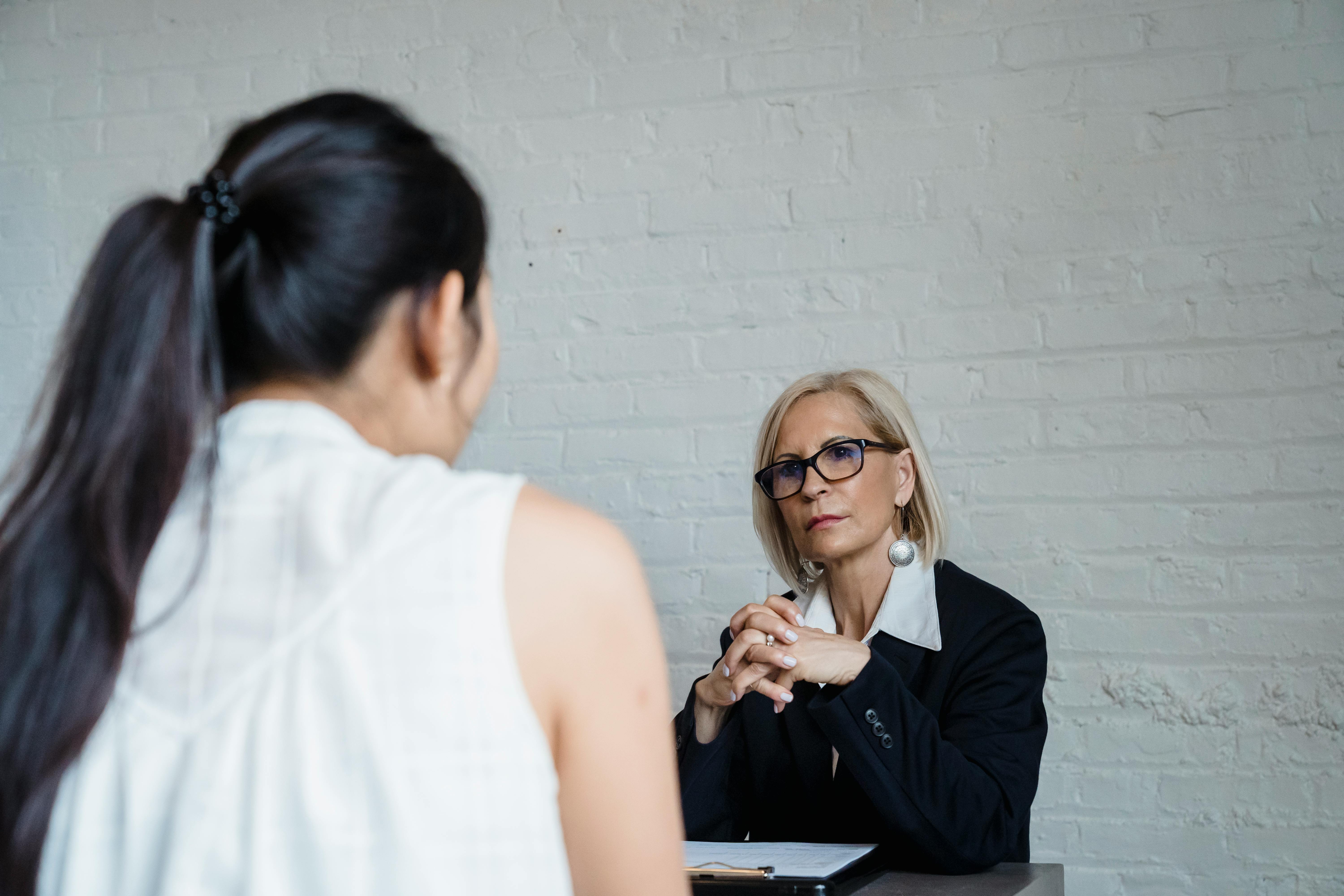 Adult Woman Seriously Listening to the Person Wearing White Sleeveless Shirt