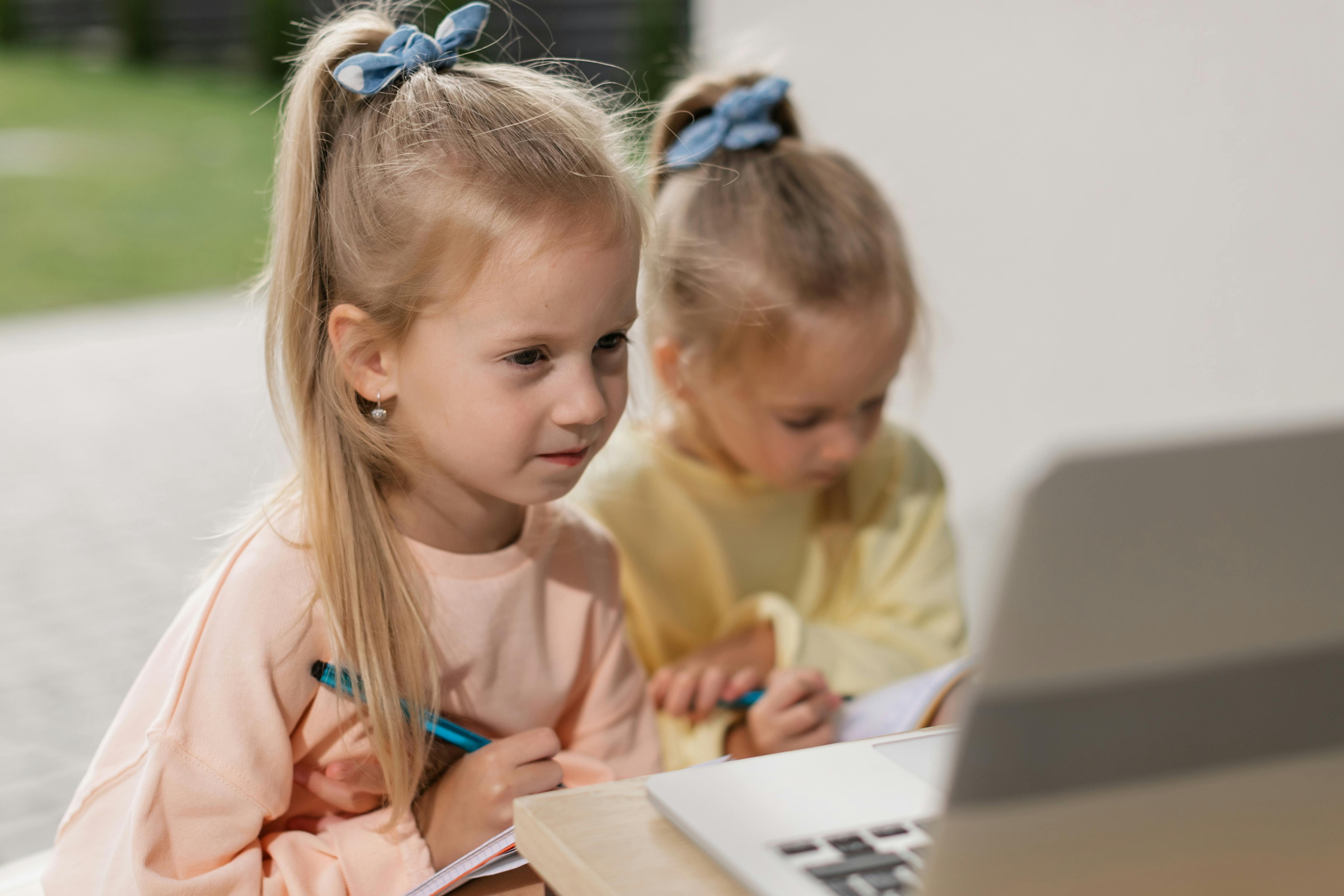 Close-Up Shot of Two Girls Having an Online Class while Writing