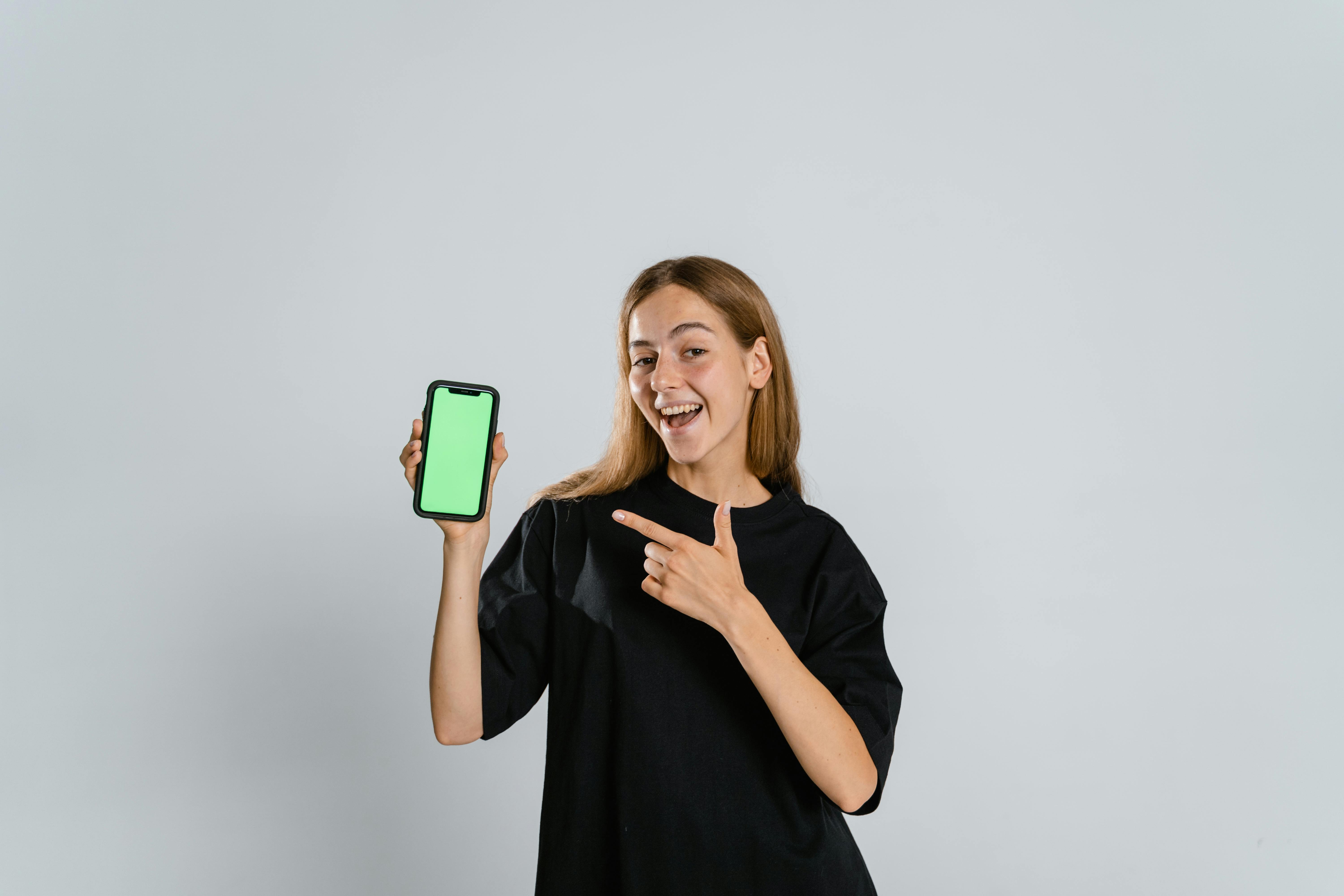Woman in Black Crew Neck T-shirt Holding Green and White Iphone Case