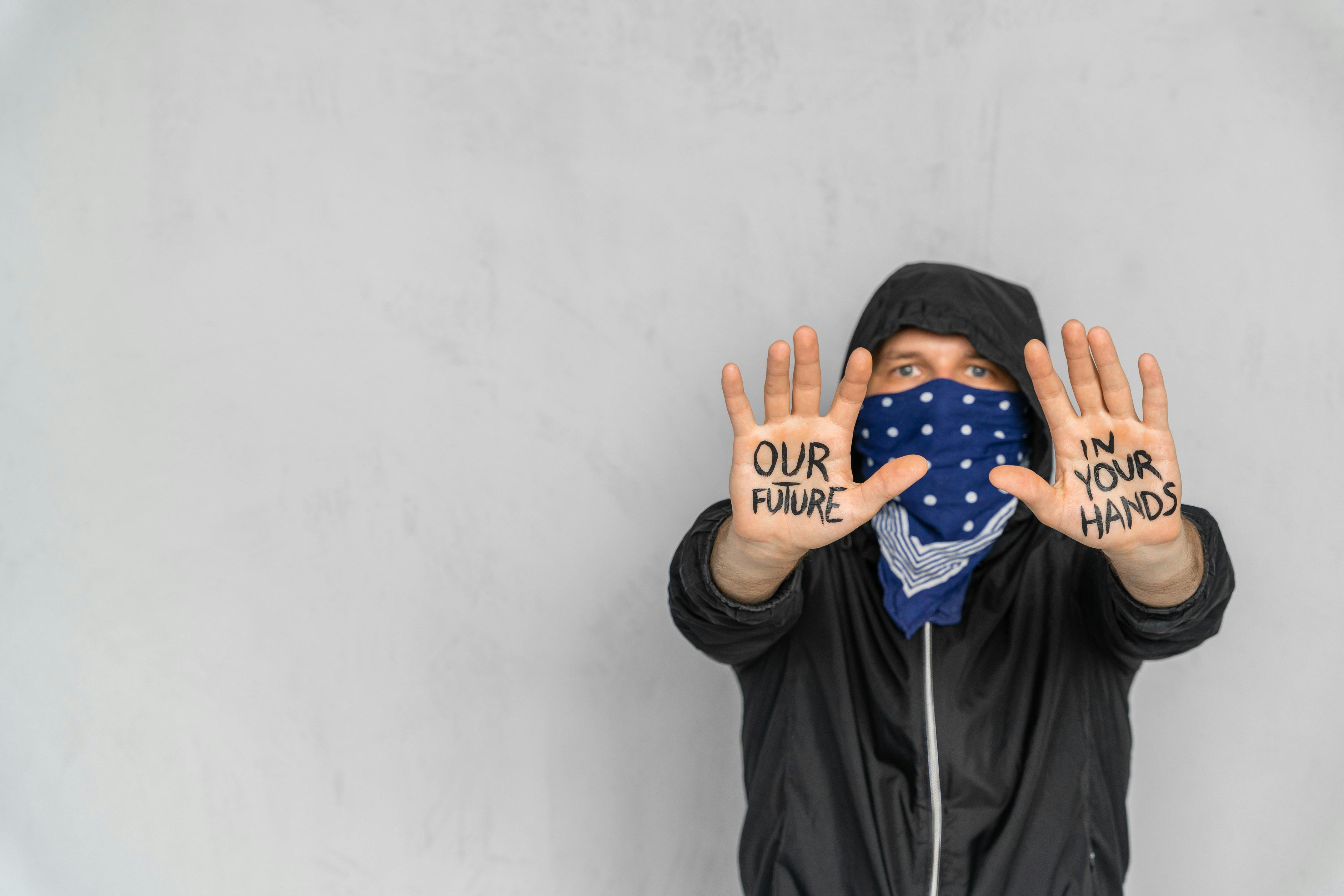 A Person Covering his Face with Scarf Showing Message Written on his Hands