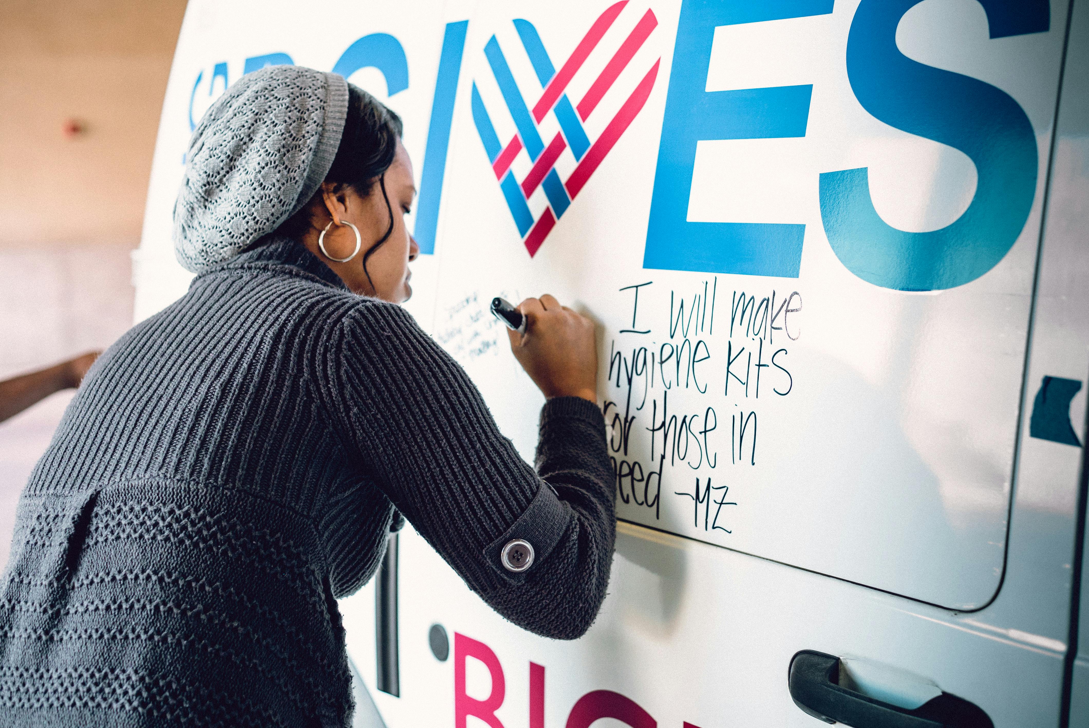 A black female writing a message at the back of a van