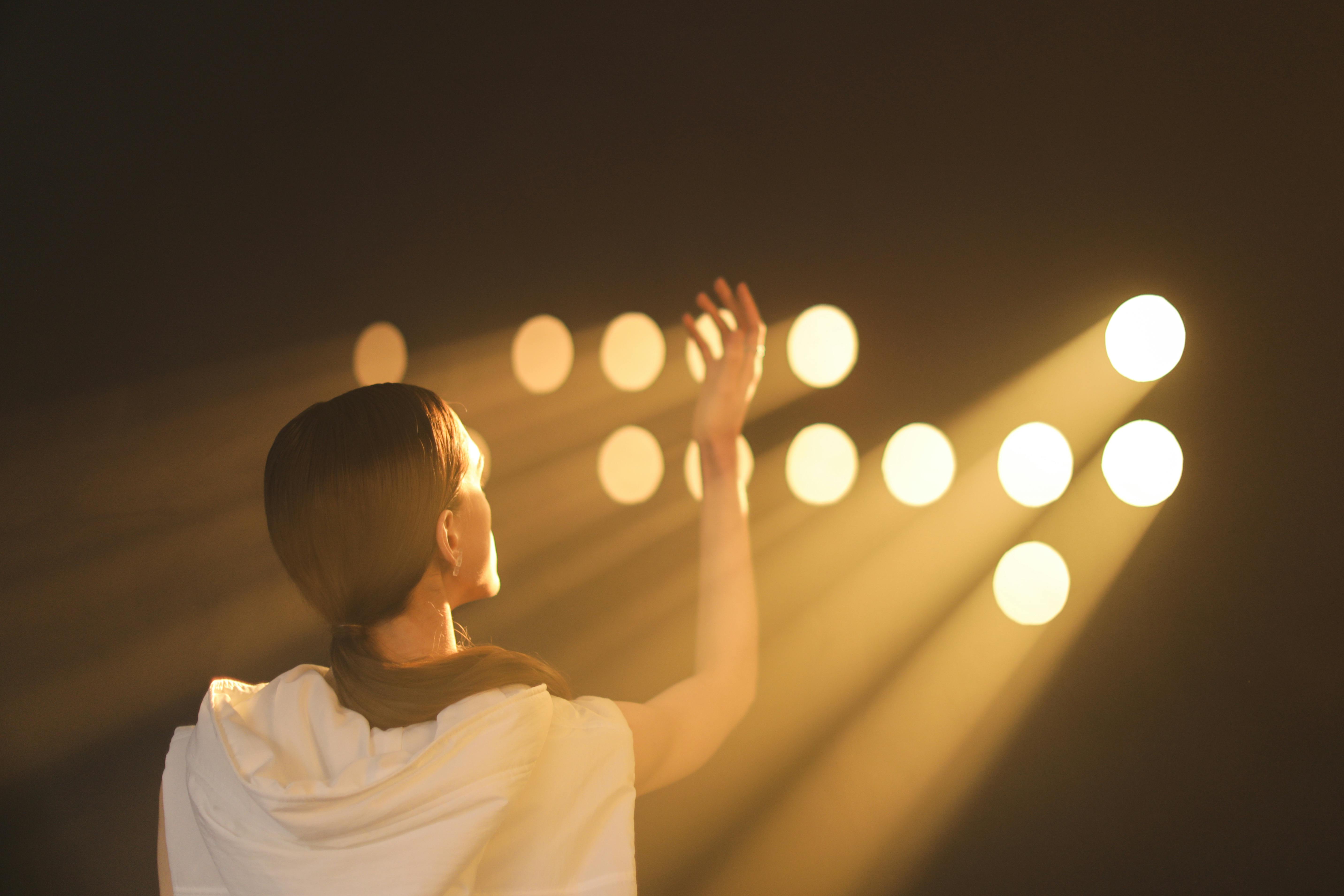 Circles of Lights over Woman Standing with Hand Raised