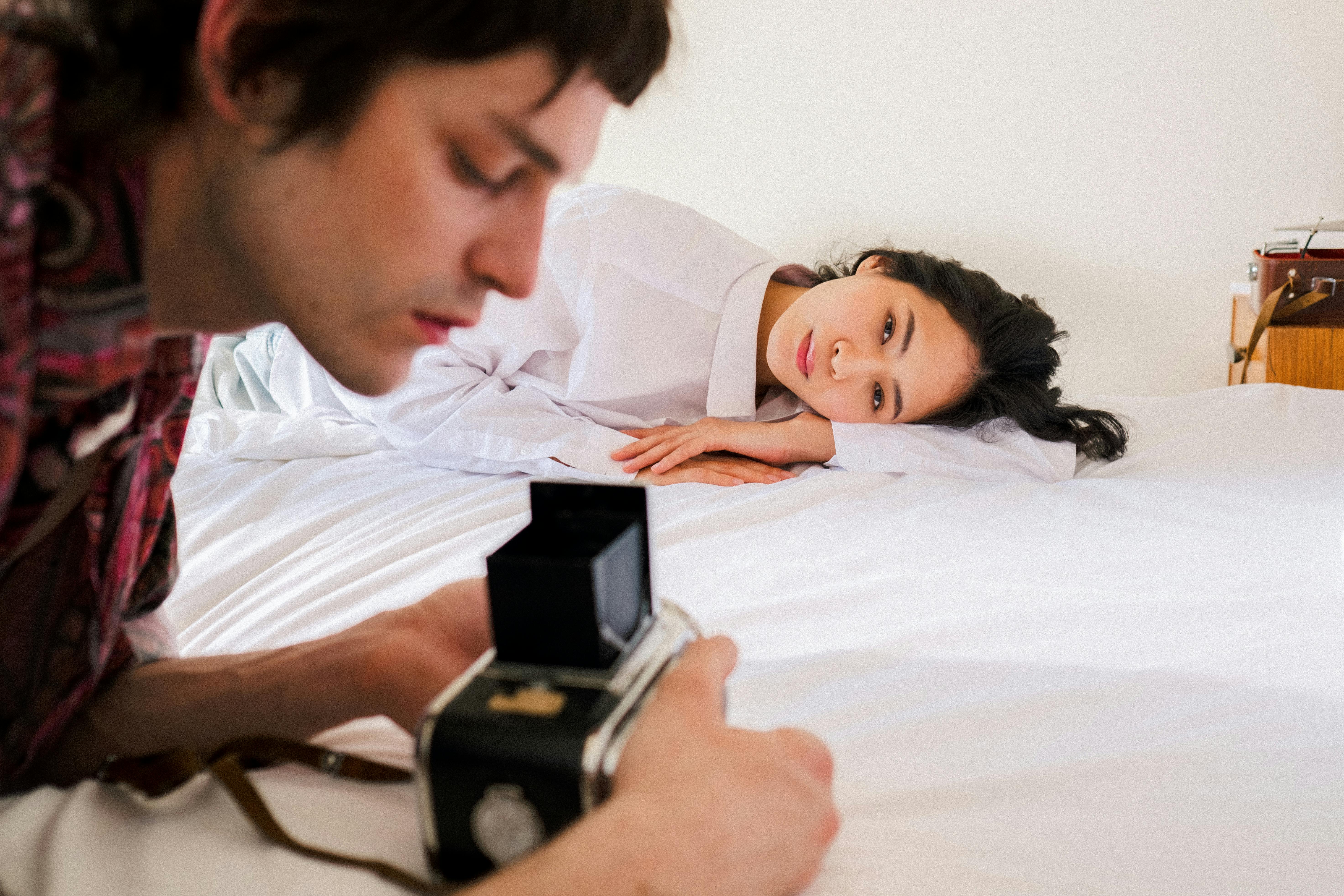 Man Taking Photo of a Woman on Bed