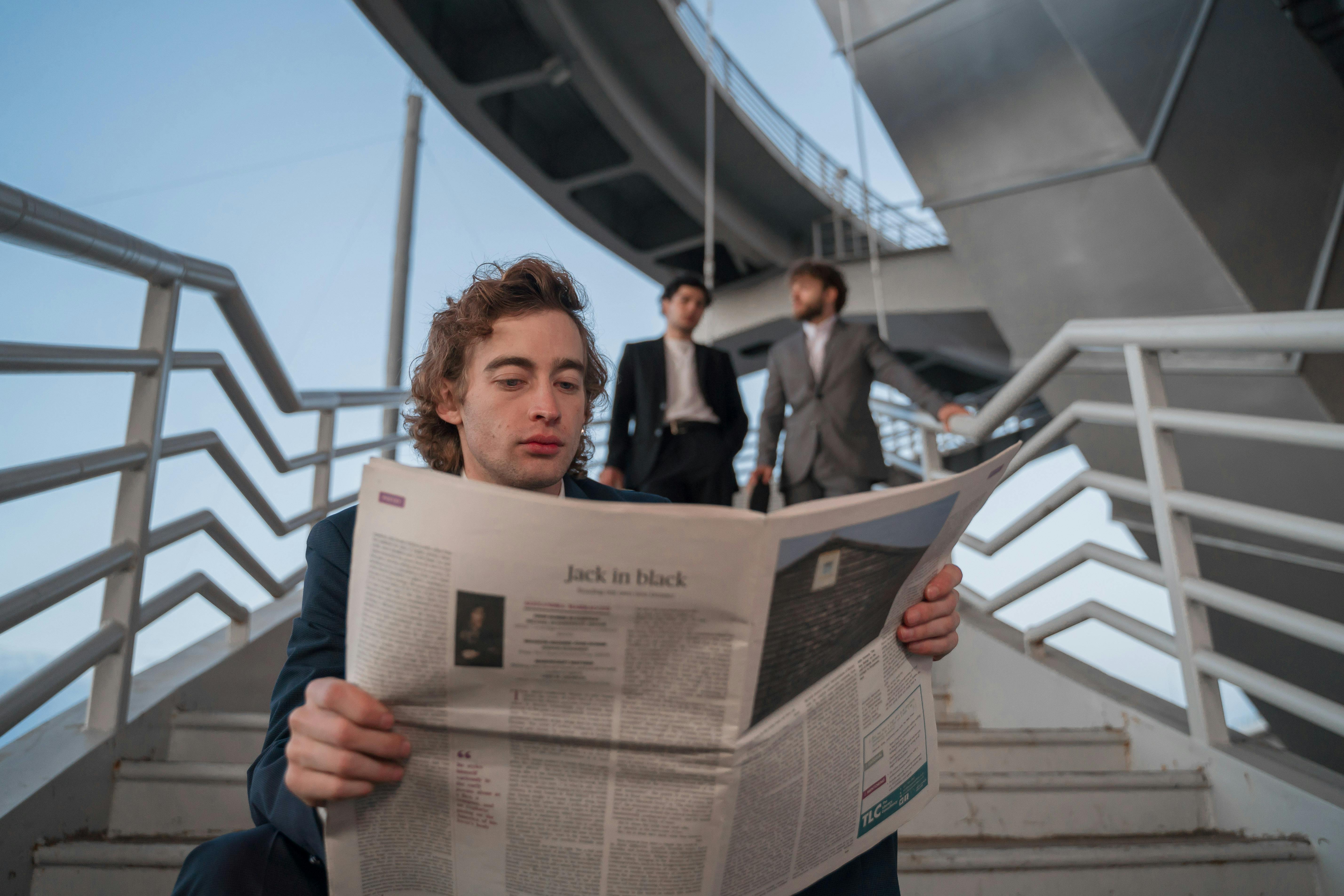 Low-Angle Shot of a Man with Curly Hair Reading a Newspaper