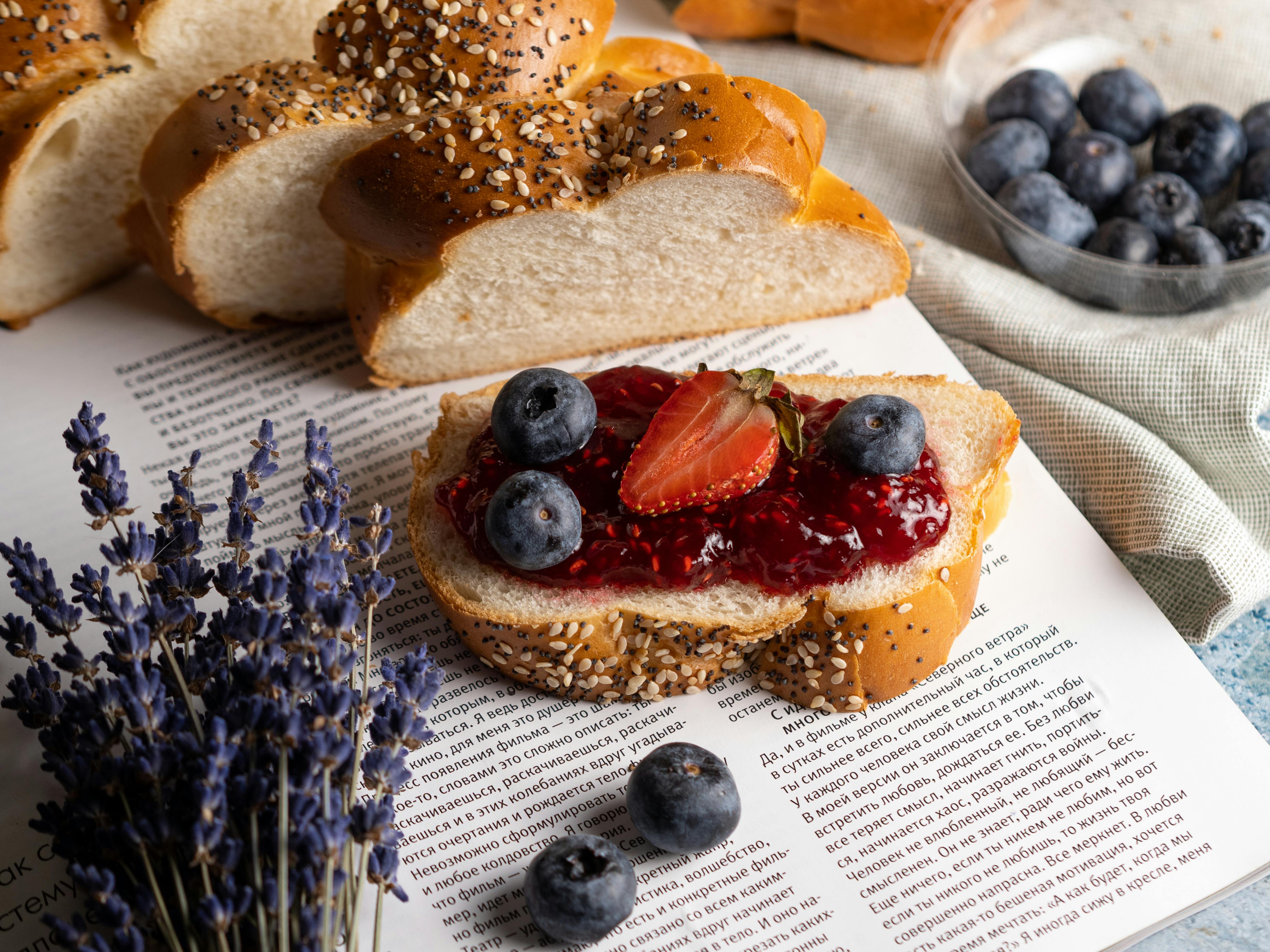 Fresh Slice of Bread with Jam and Fruits Lying on Open Book