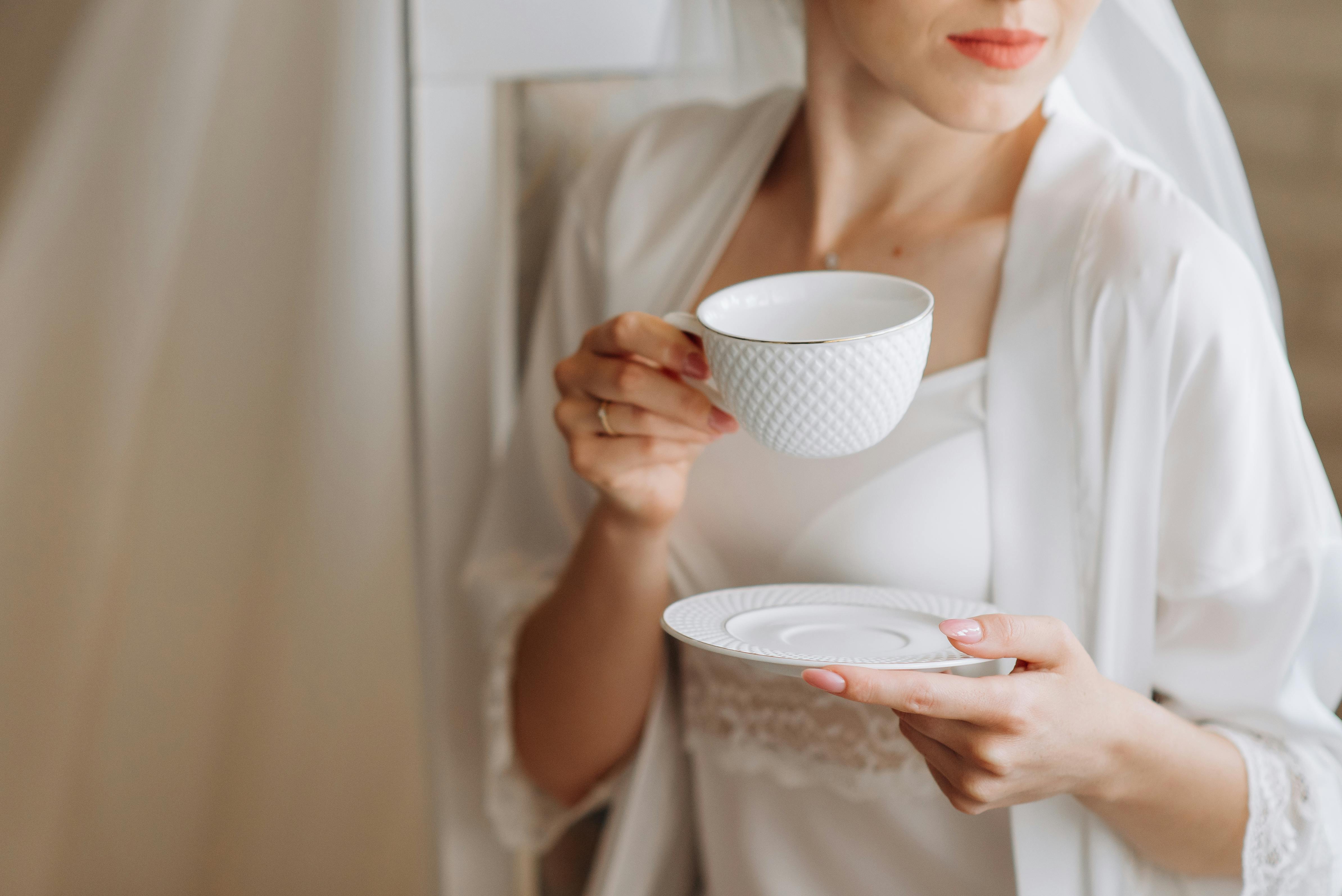 Woman in White Silk Dressing Gown and Nightwear Holding a White Cup of Coffee