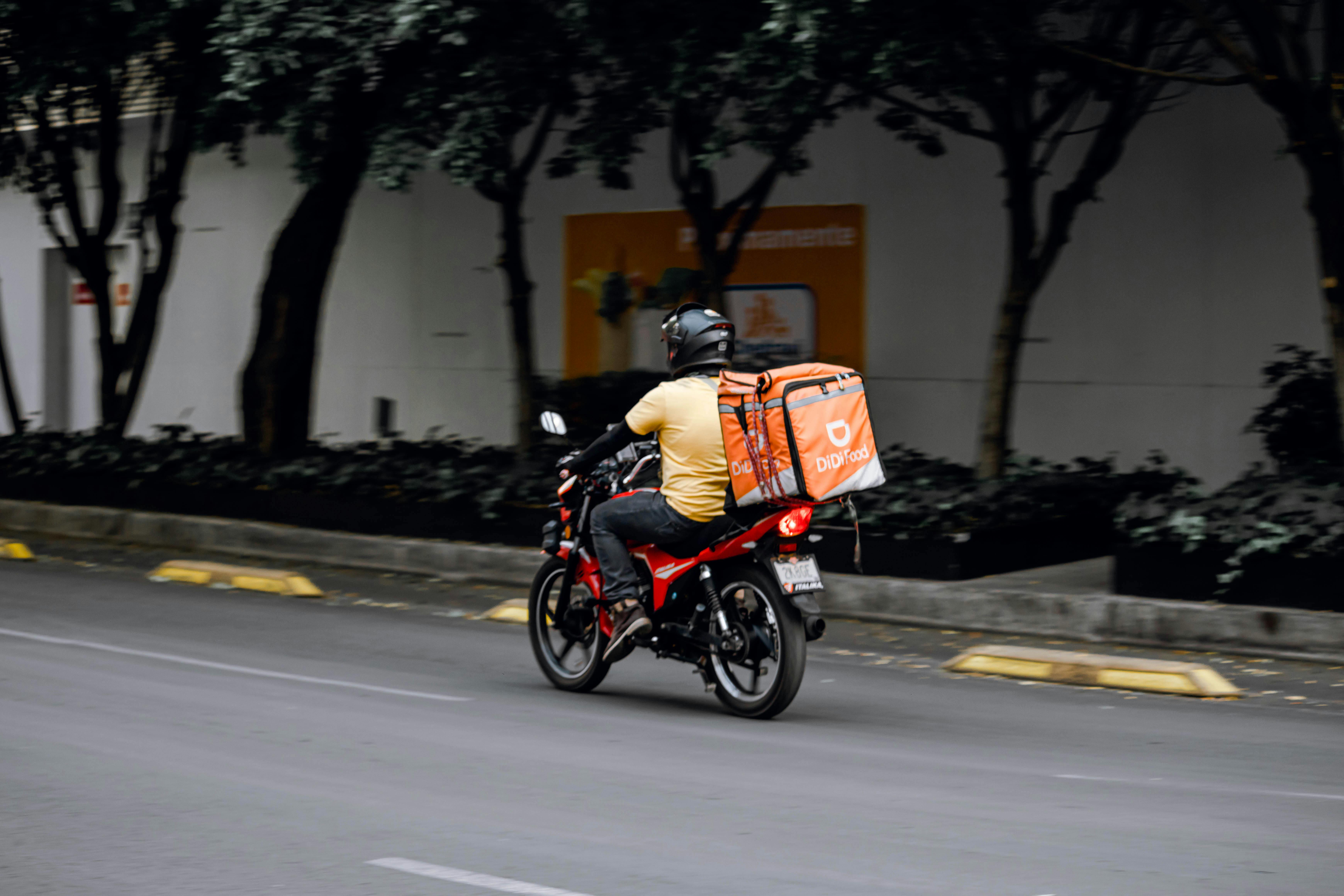 A Delivery Man Riding a Motorcycle on Road