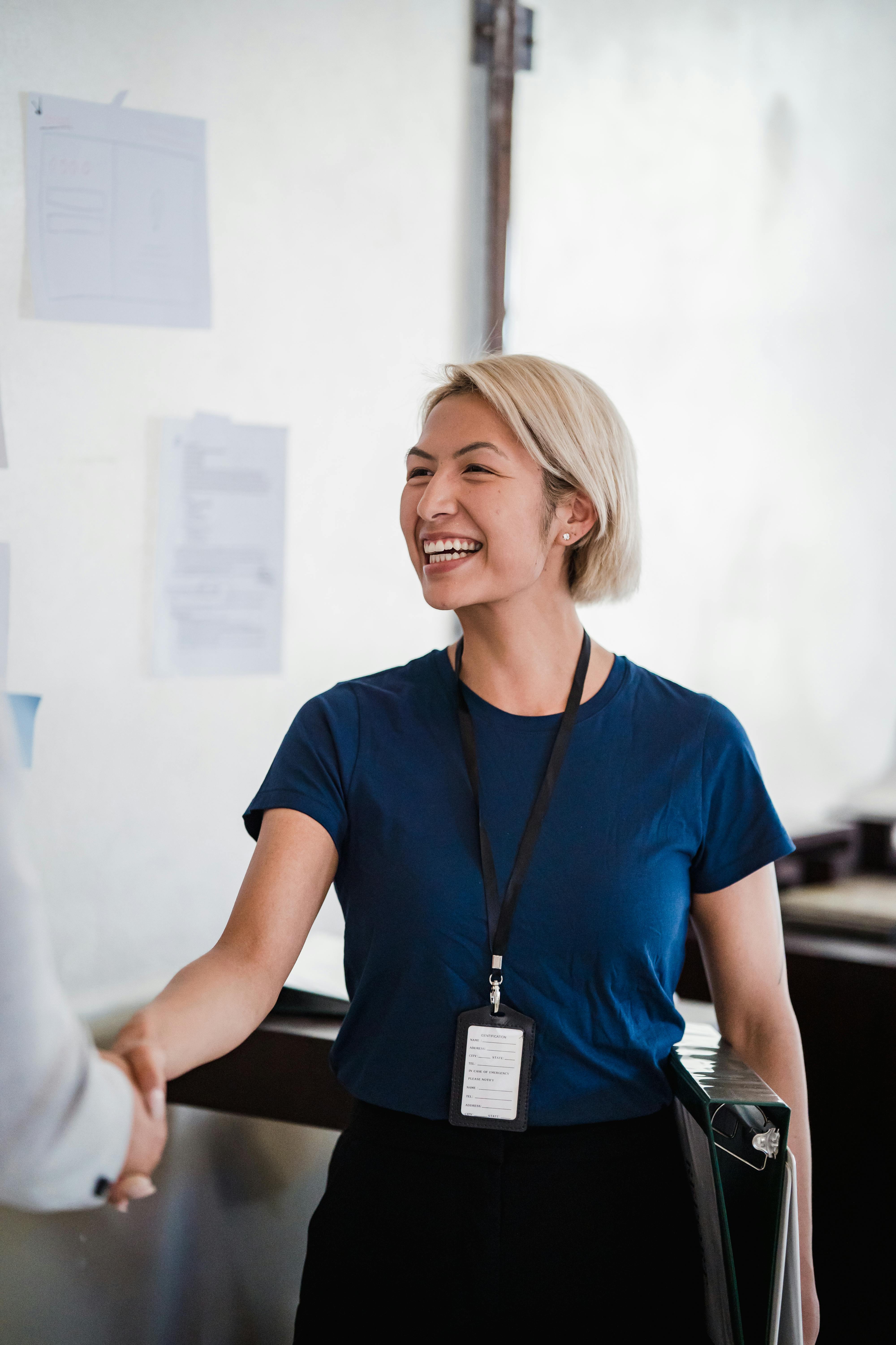 Smiling Woman Shaking Hands with Person in Office