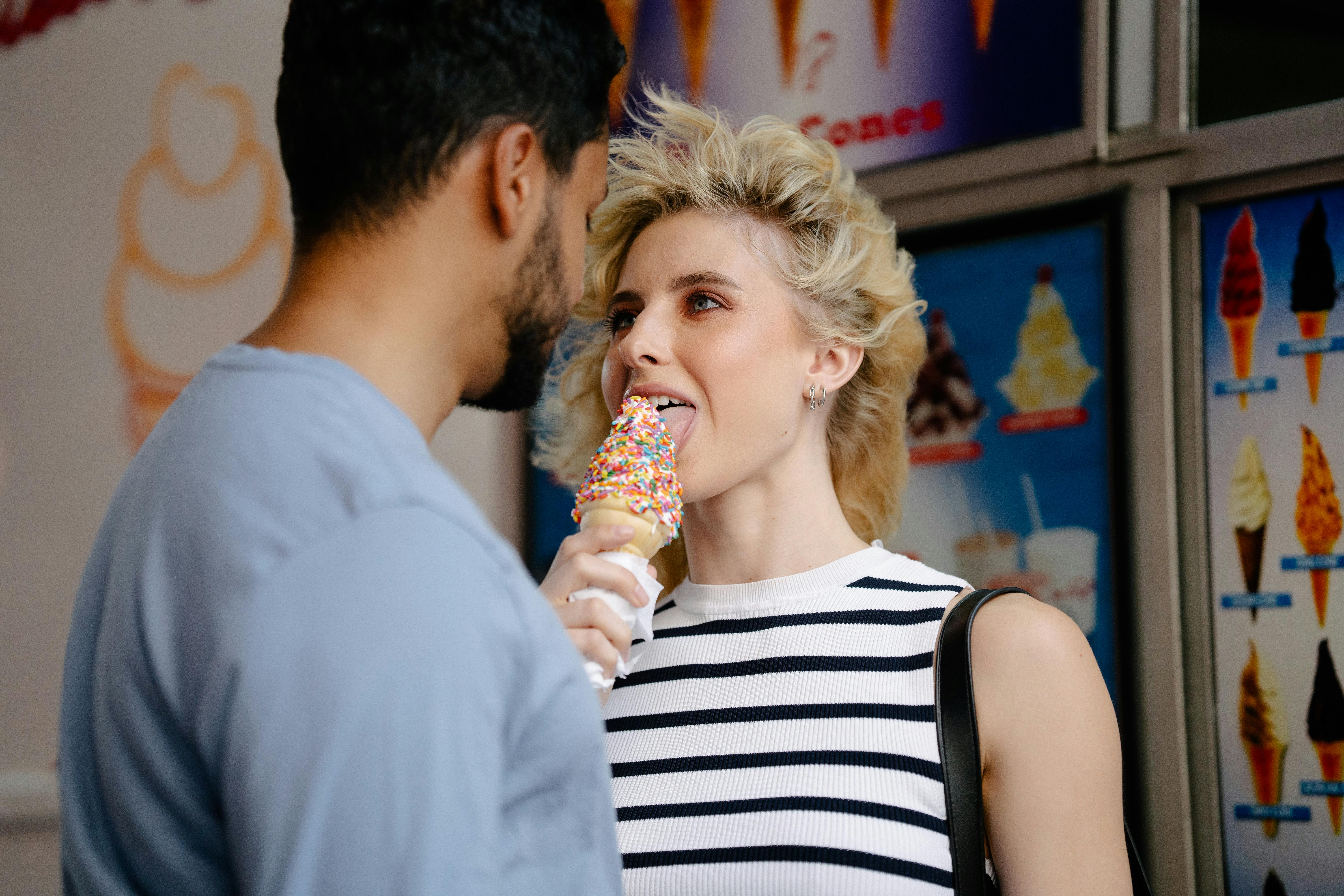 Woman with Tousled Hair Licking an Ice Cream and Looking in Man's Eyes