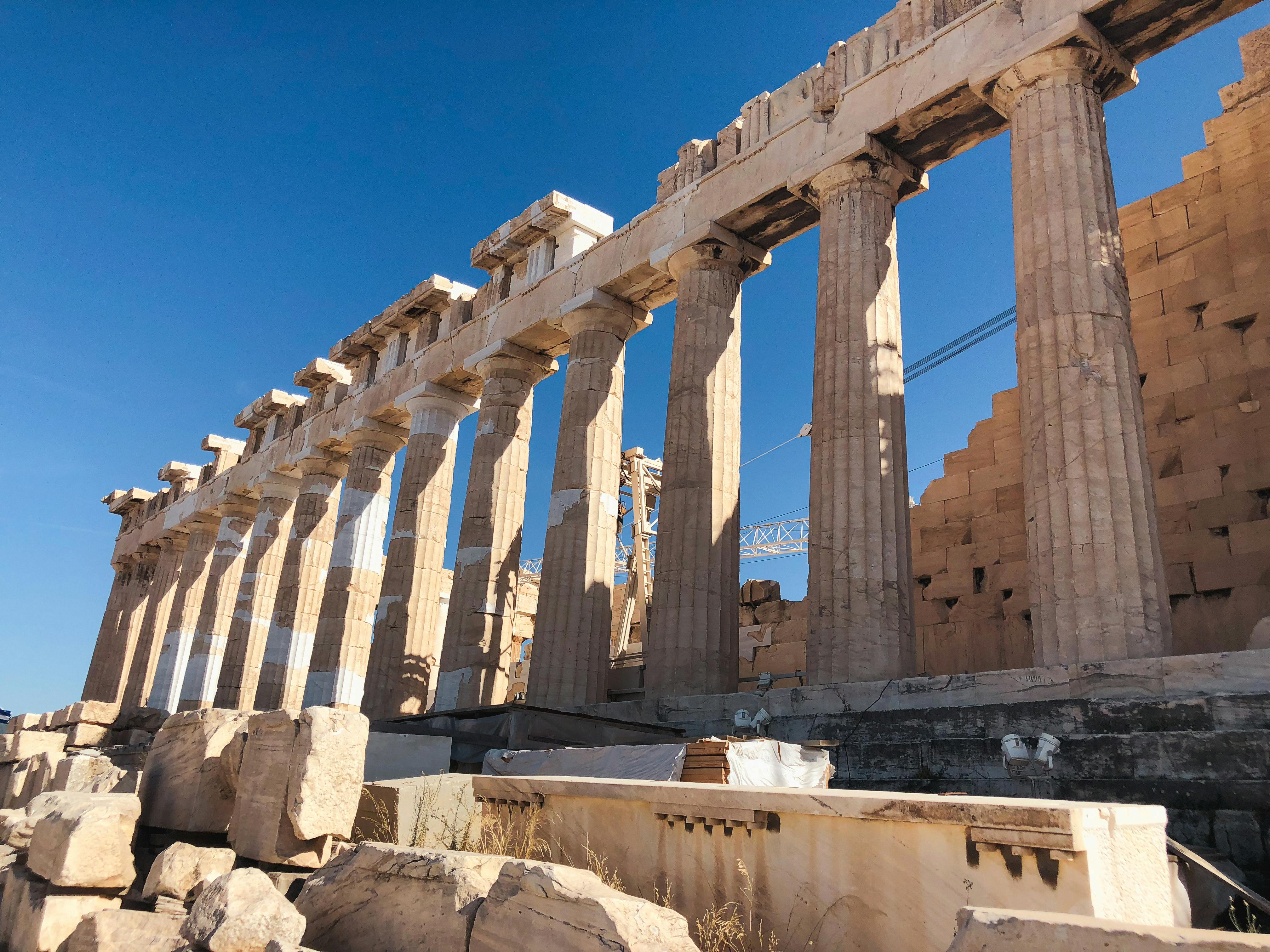 A side view of the Parthenon standing on the Acropolis on a sunny blue sky day