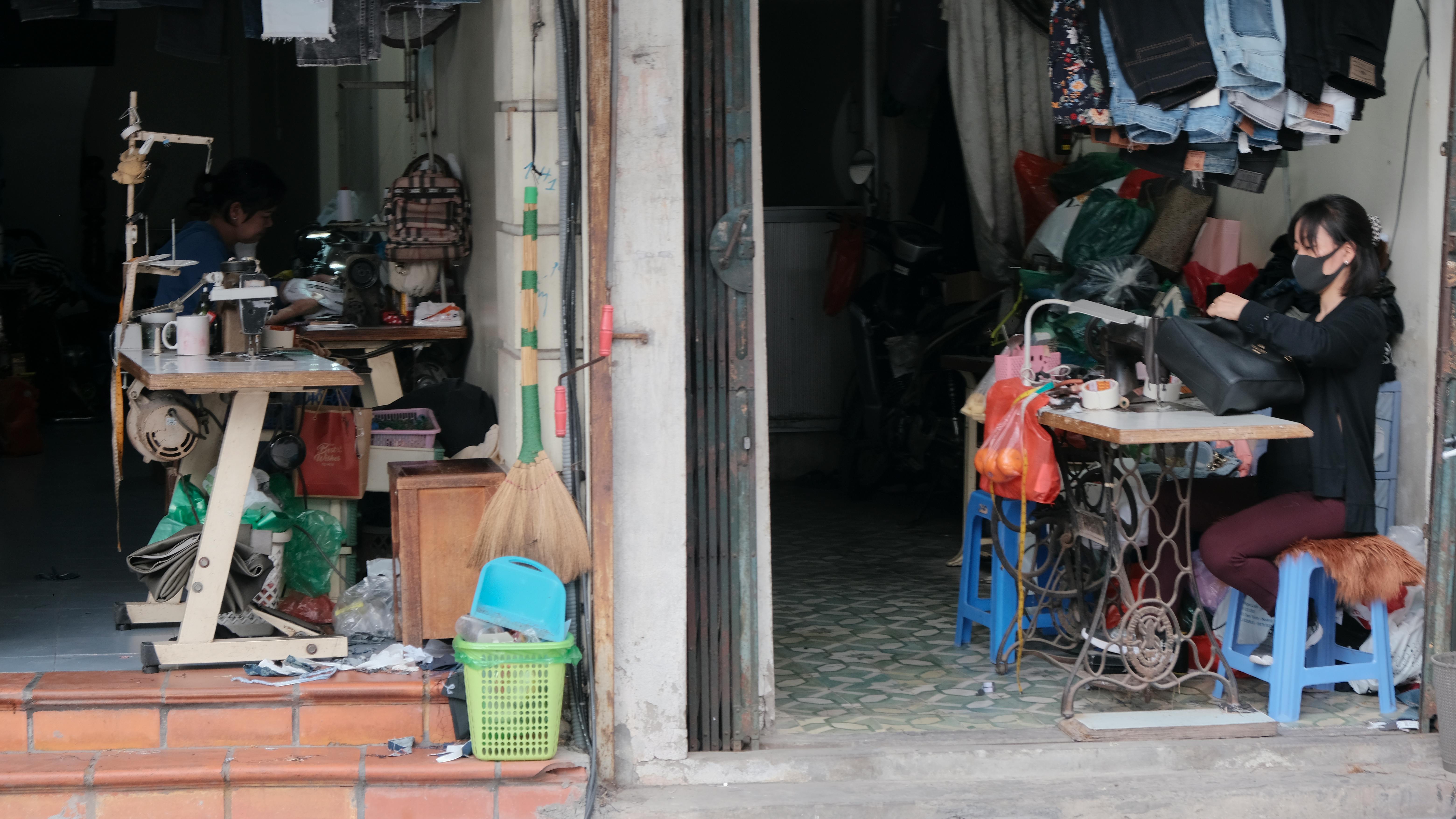 A Person Wearing Facemask Sitting in Front of Sewing Machine with a Black Bag