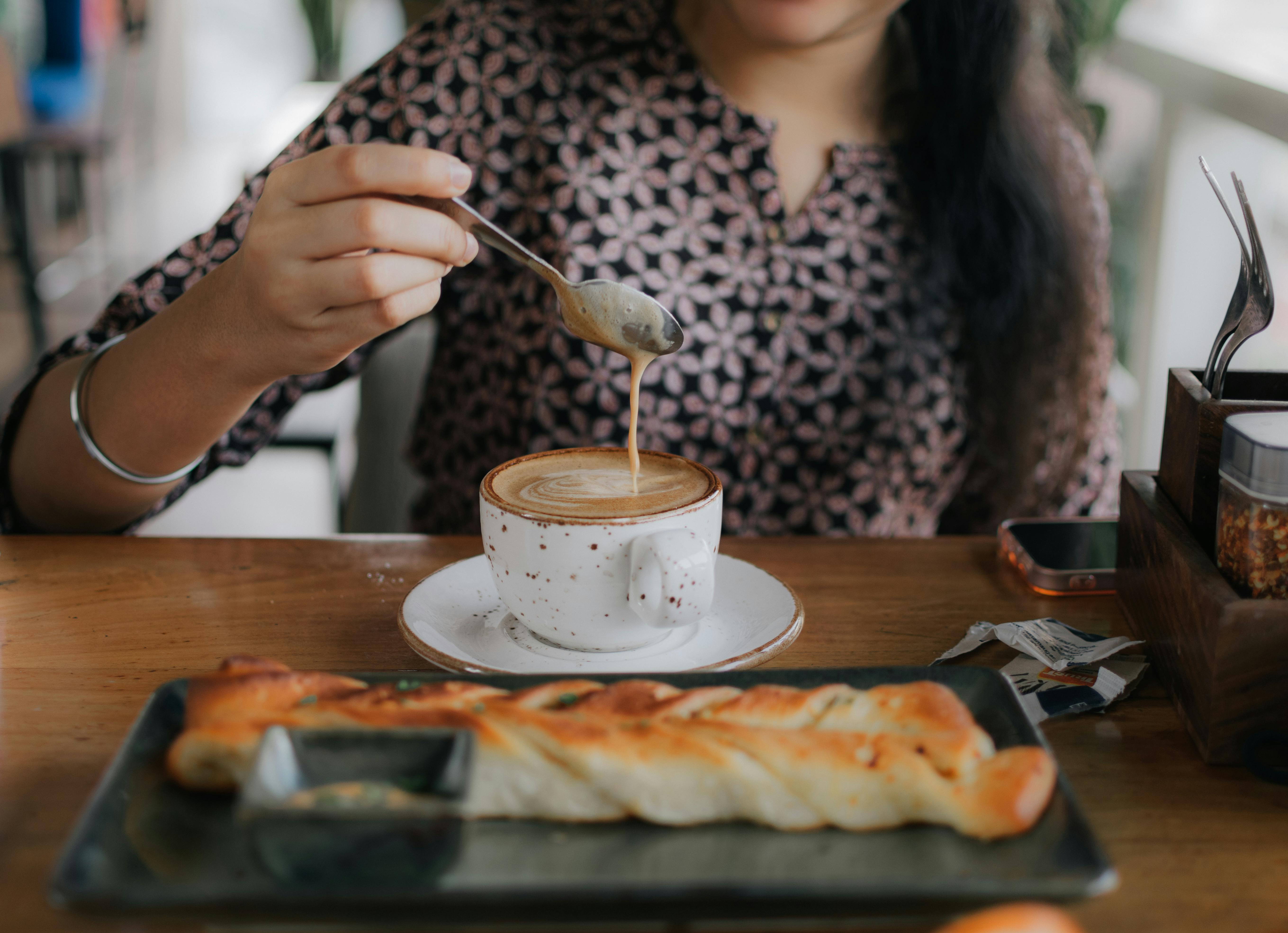 Woman Drinking Coffee at Table in Cafe
