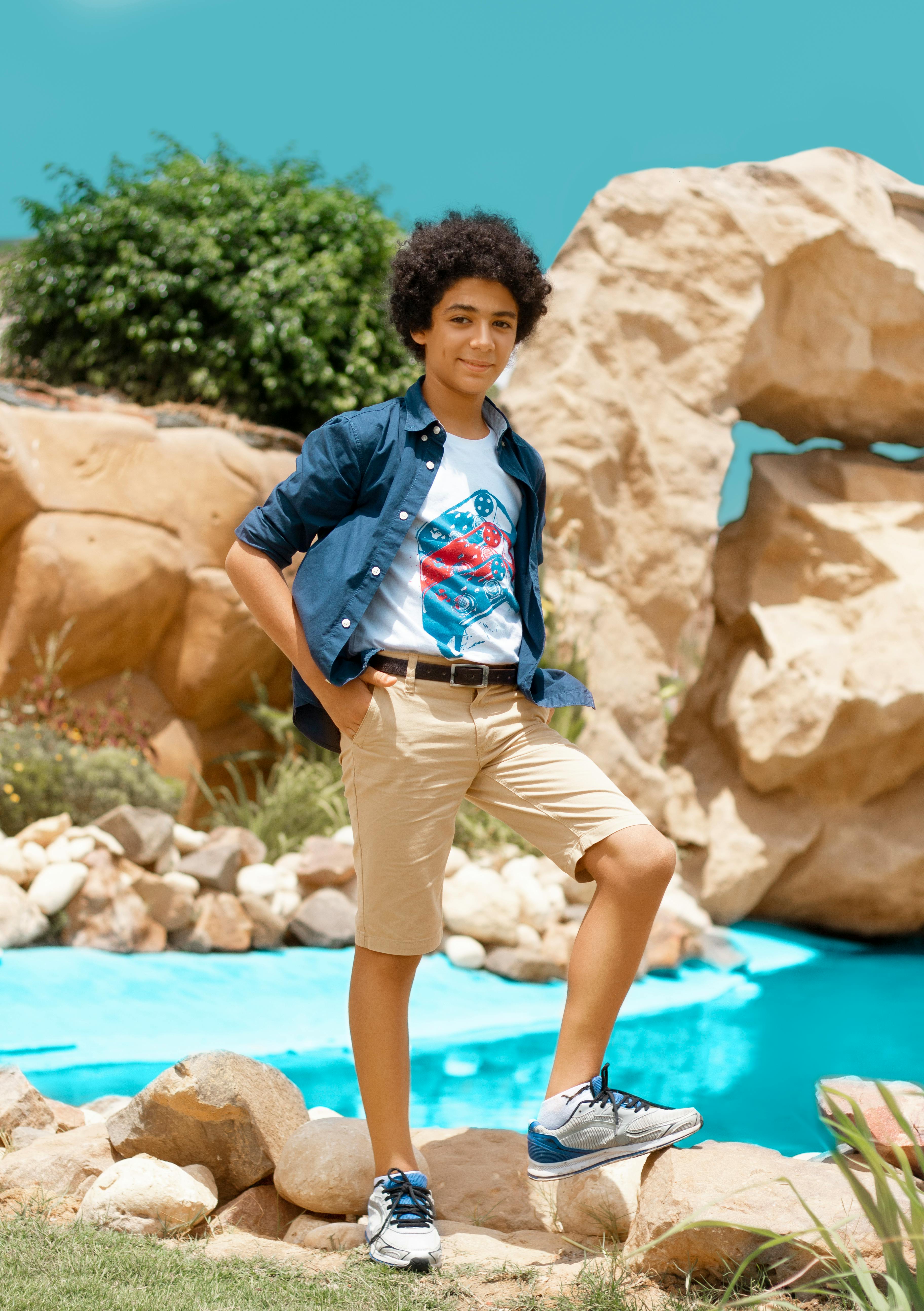 A boy standing on a rock in front of a pool