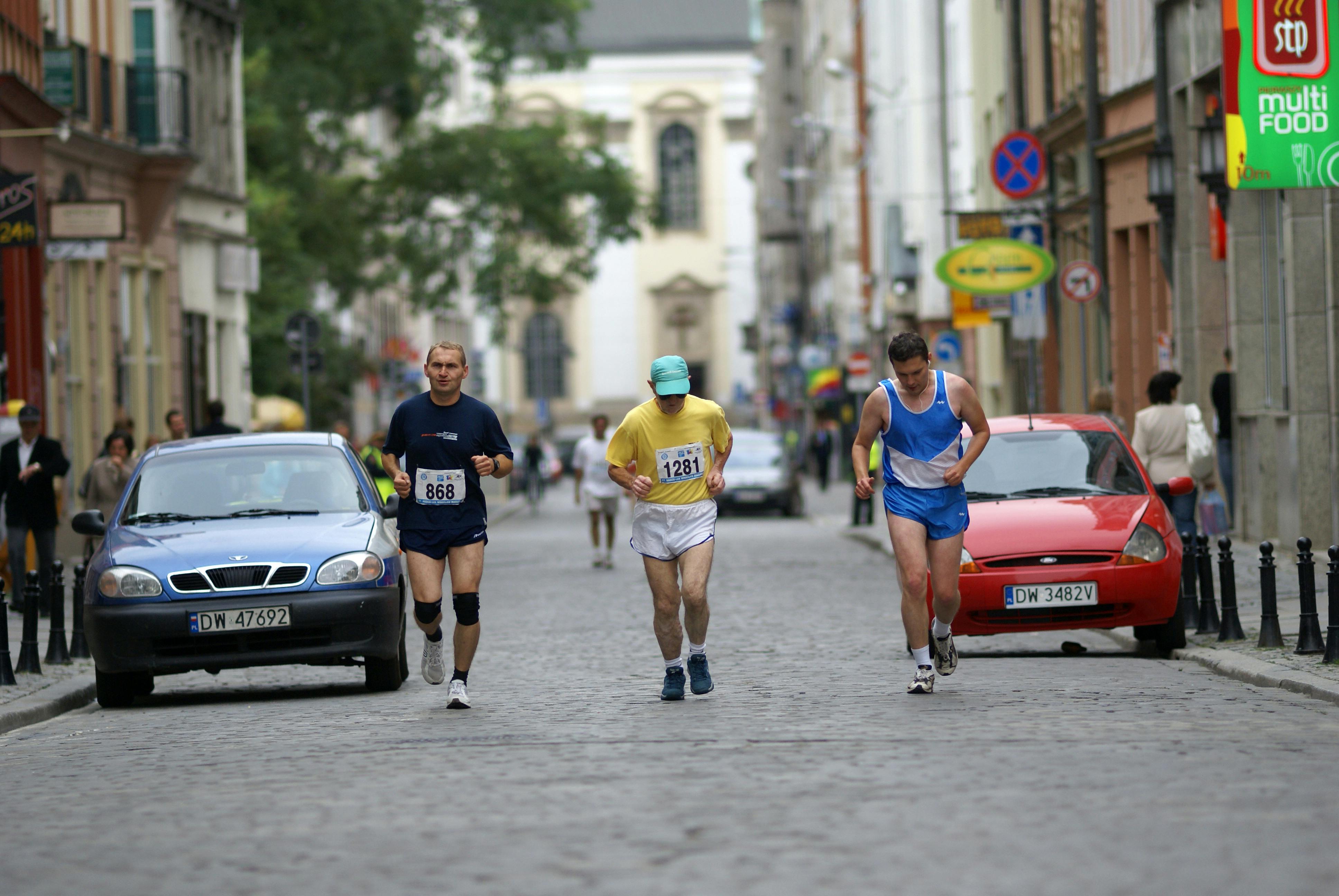 Three men running down a street in a race