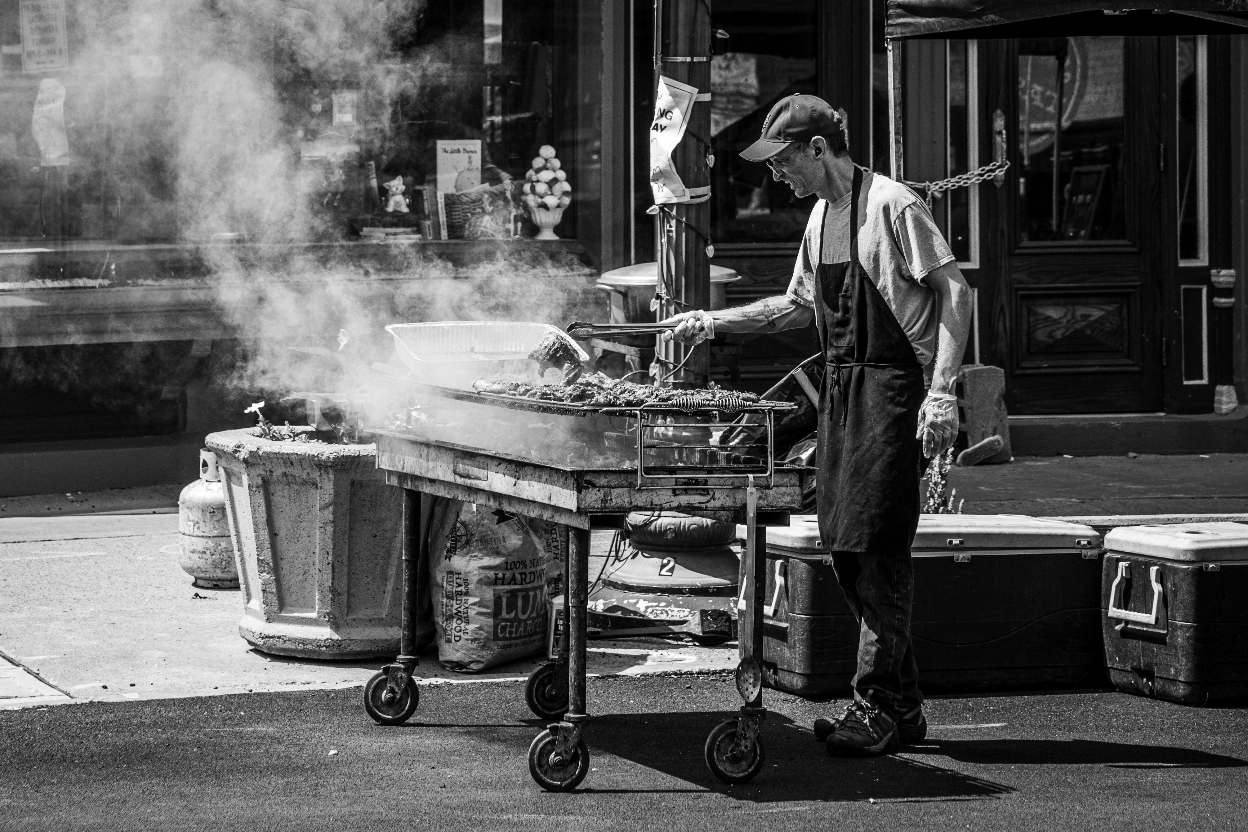 A man is cooking food on a grill in front of a building