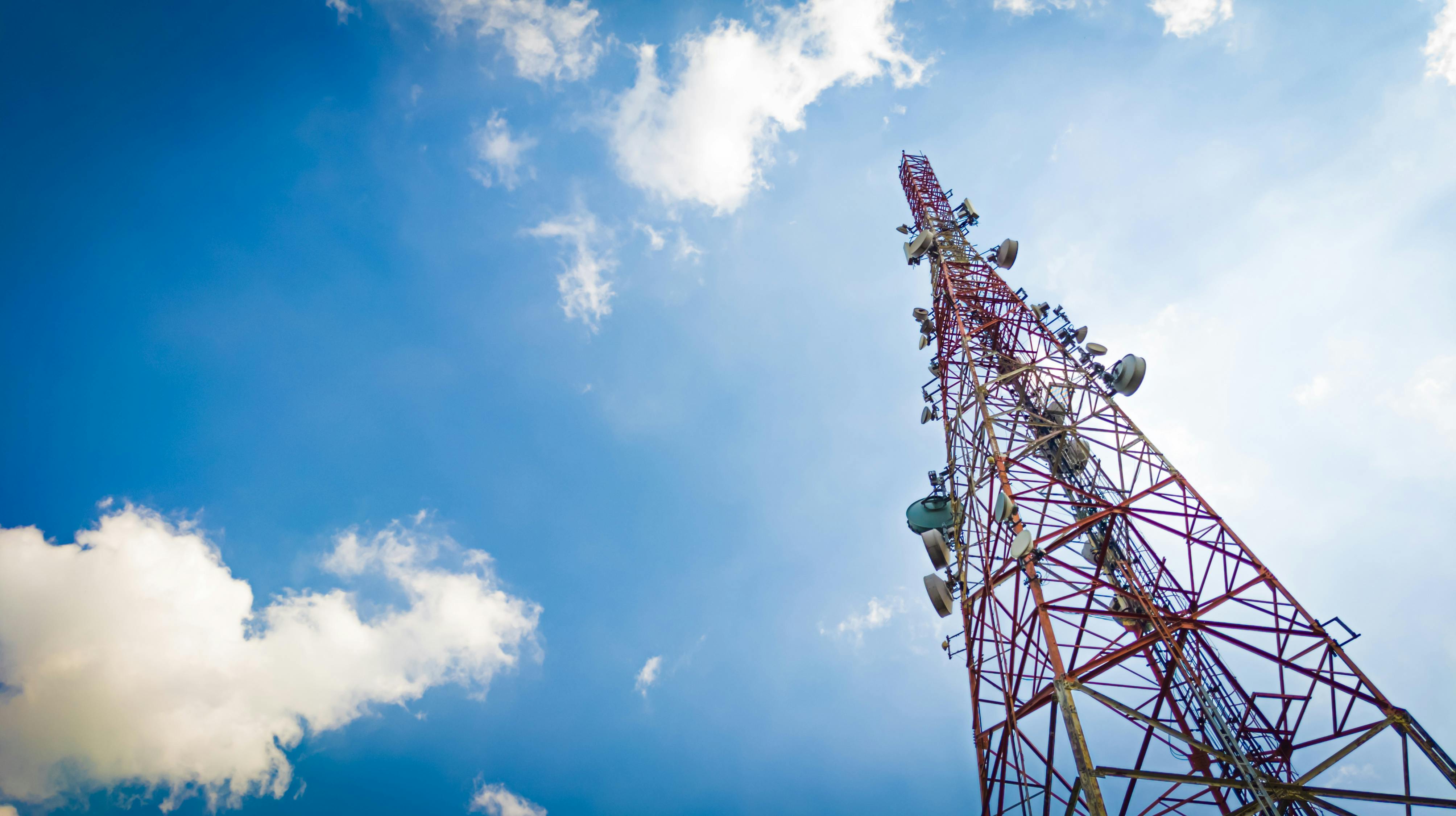 Telecommunication tower under cloudy and blue sky. Wireless communication and information technology concept