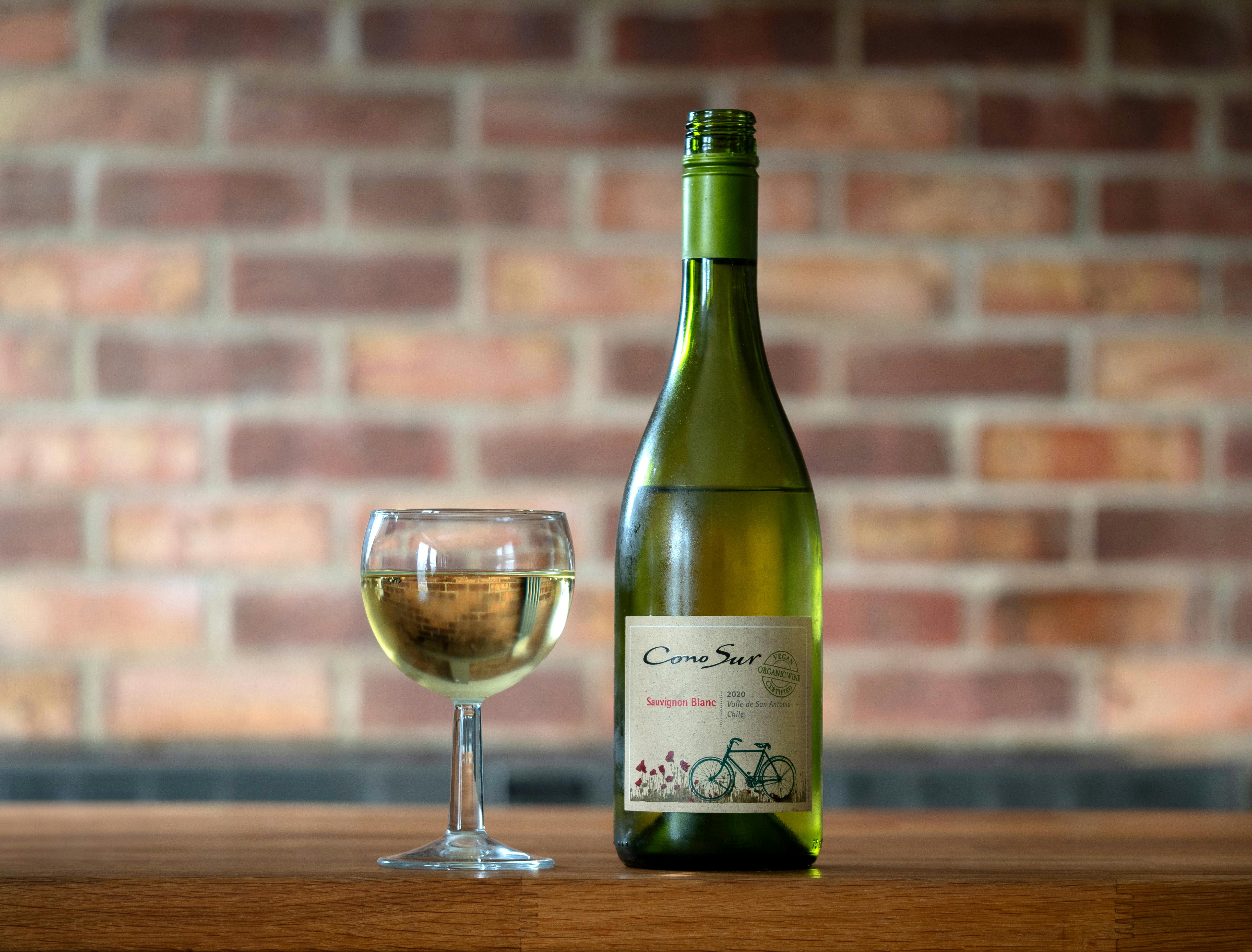 Bottle and Glass of a White Wine, against a Brick Wall