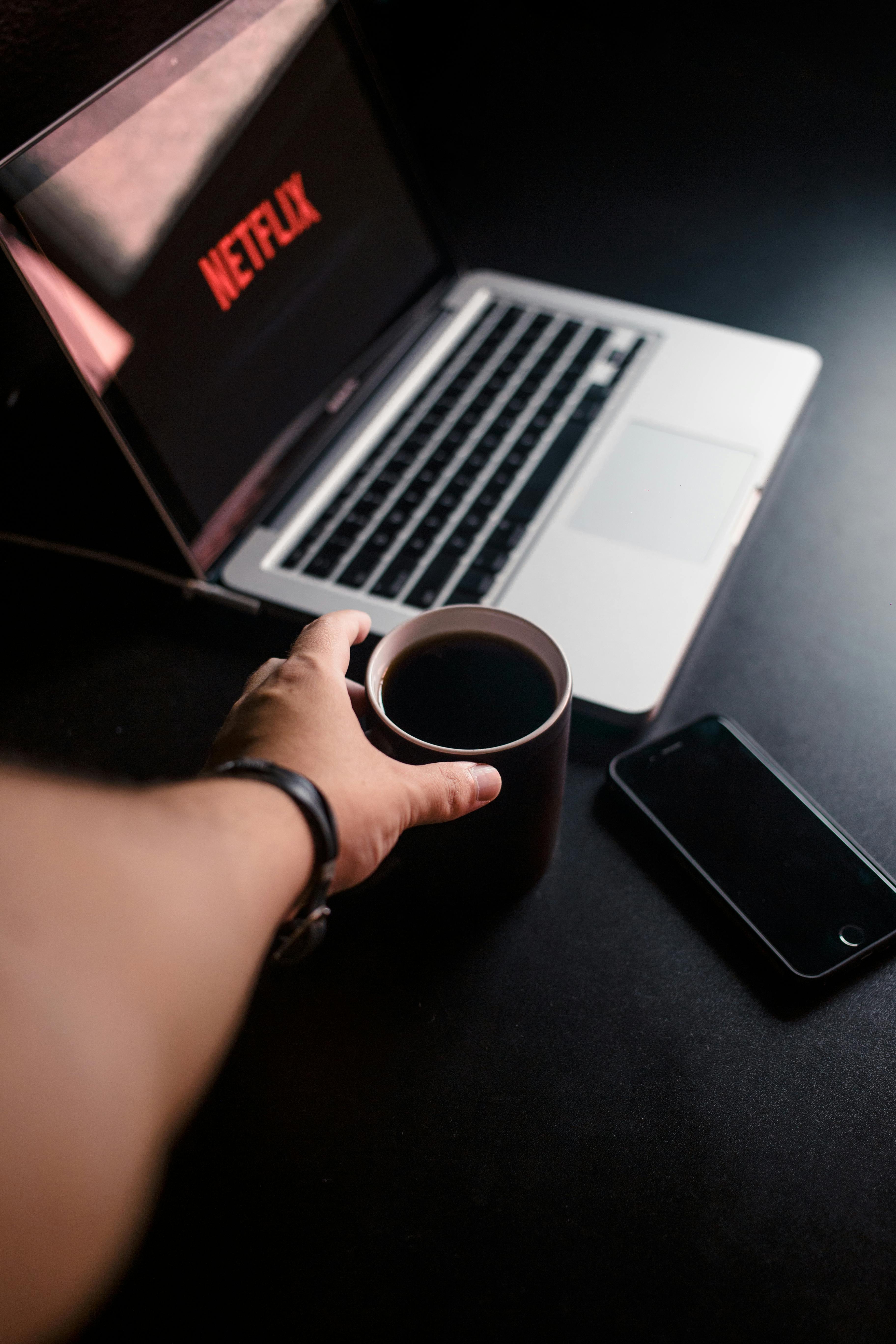 Person Reaching for Mug With Coffee Near Macbook Pro and Space Gray Iphone 6