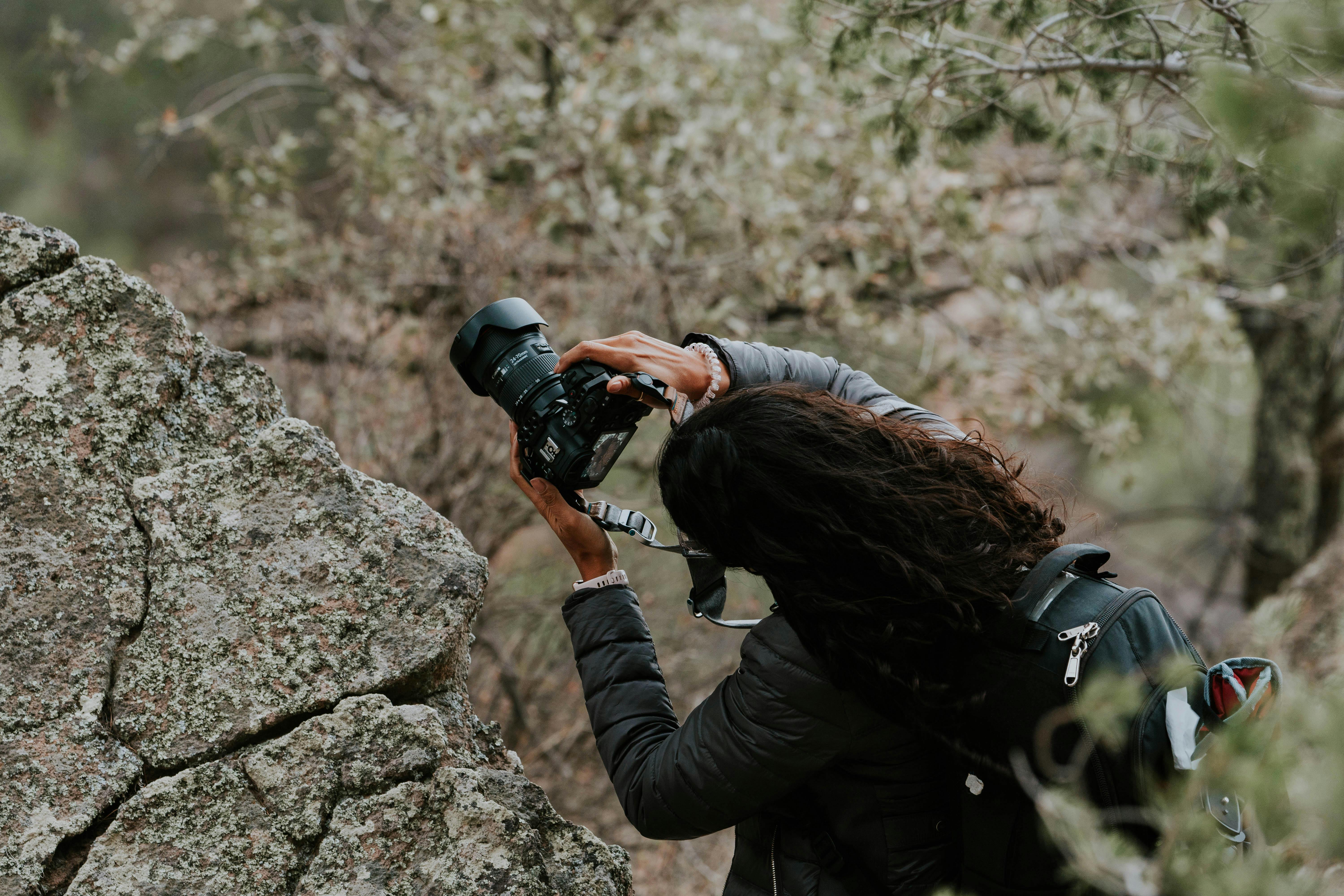 Photographer Holding Camera Among Rocks