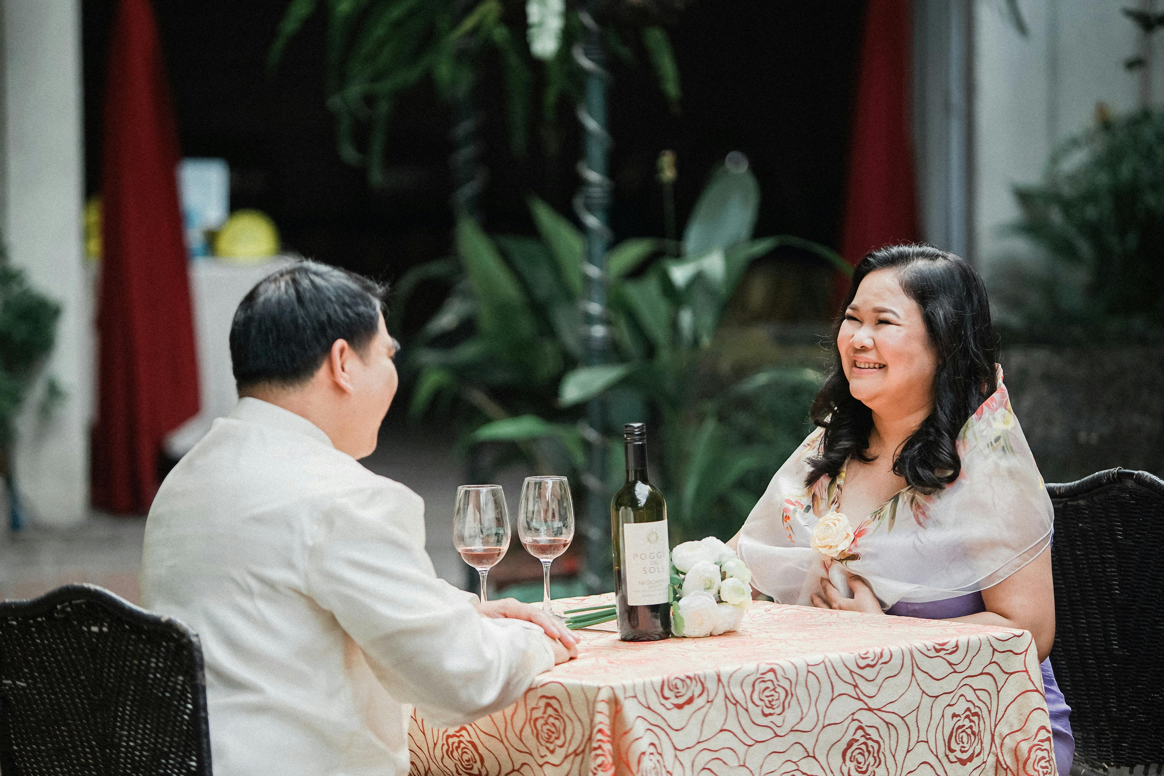 Smiling Woman Sitting with Man by Table with Wine