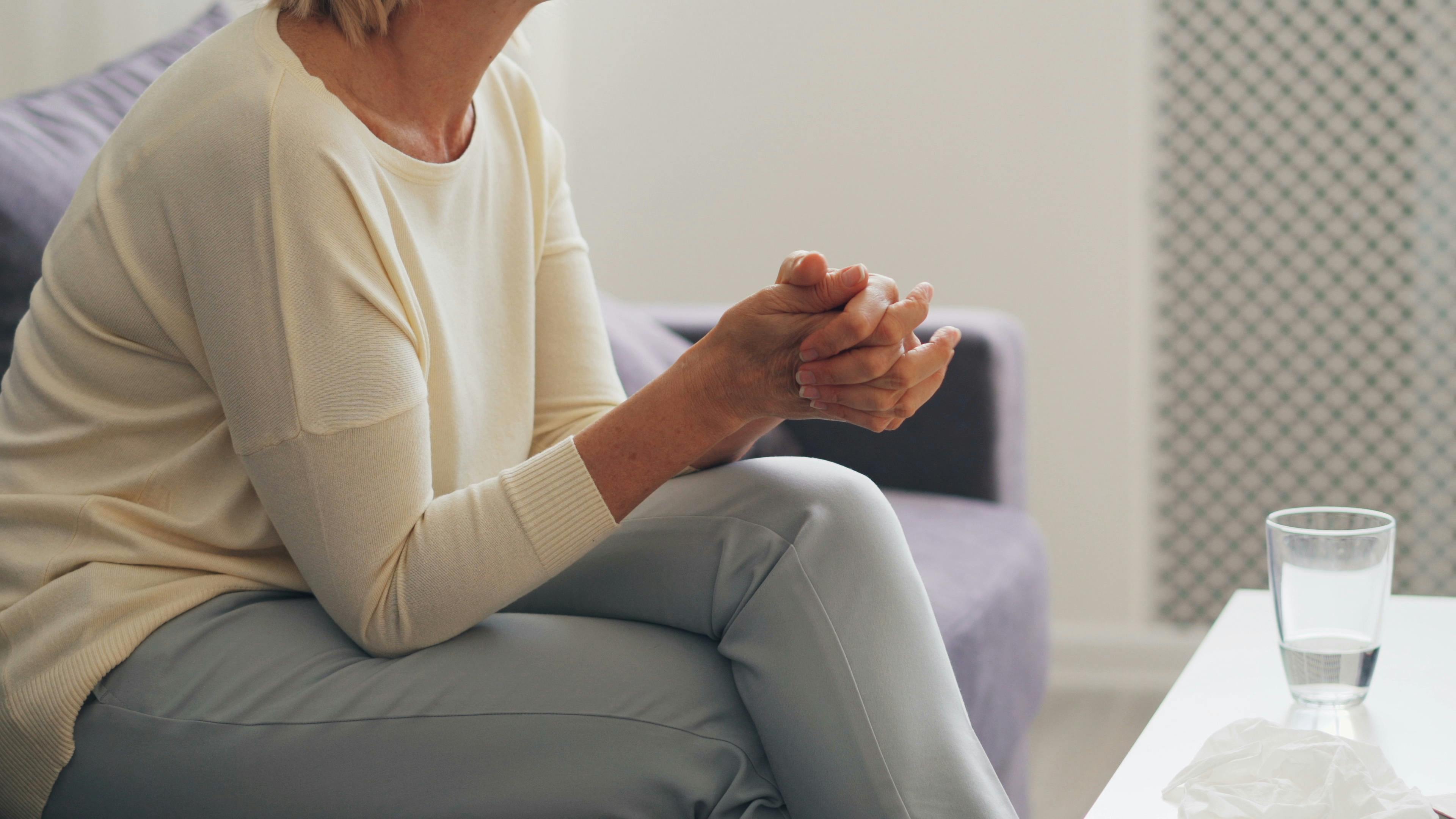 A woman sitting on a couch with her hands on her lap