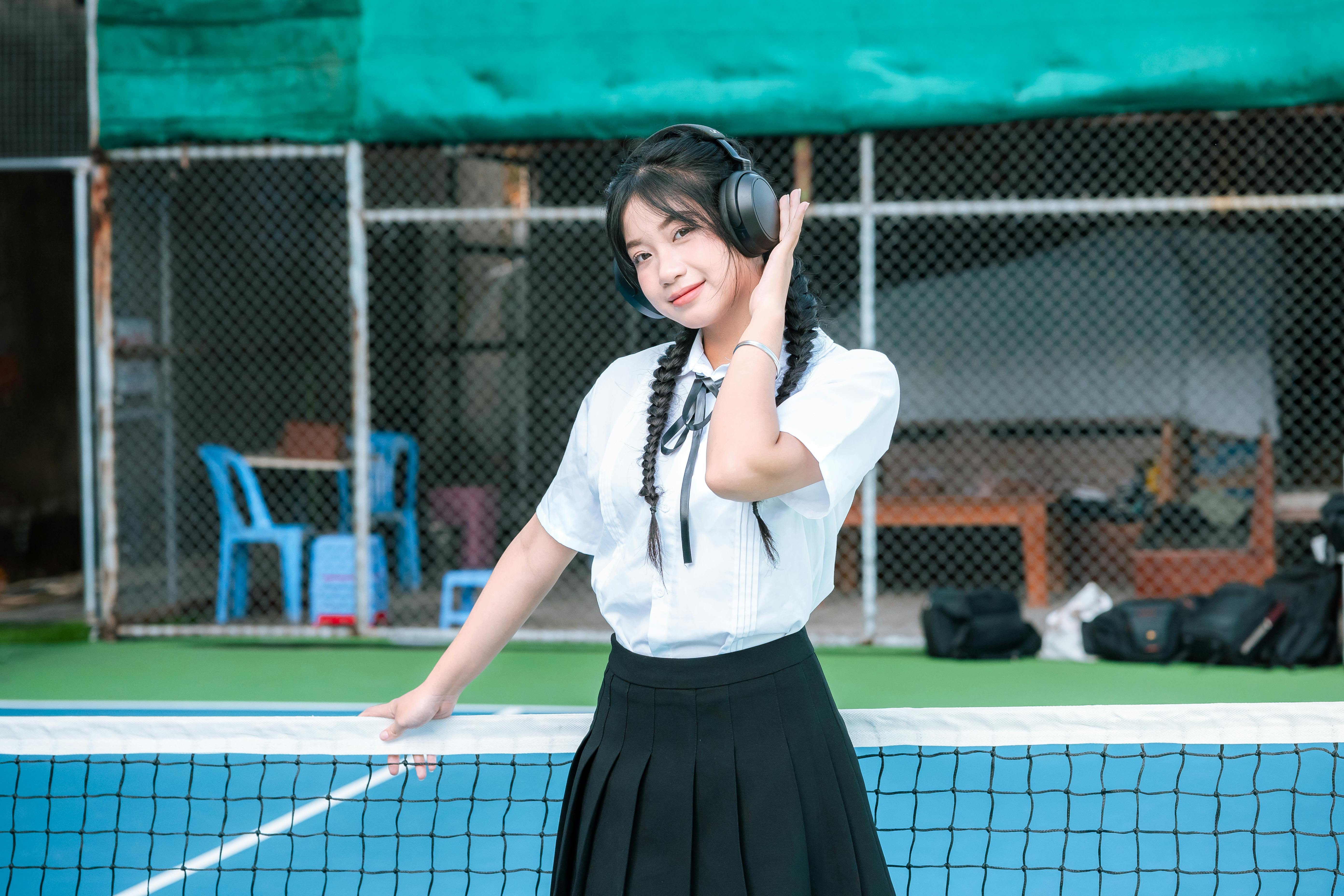 Girl Wearing Headphones on a Tennis Court