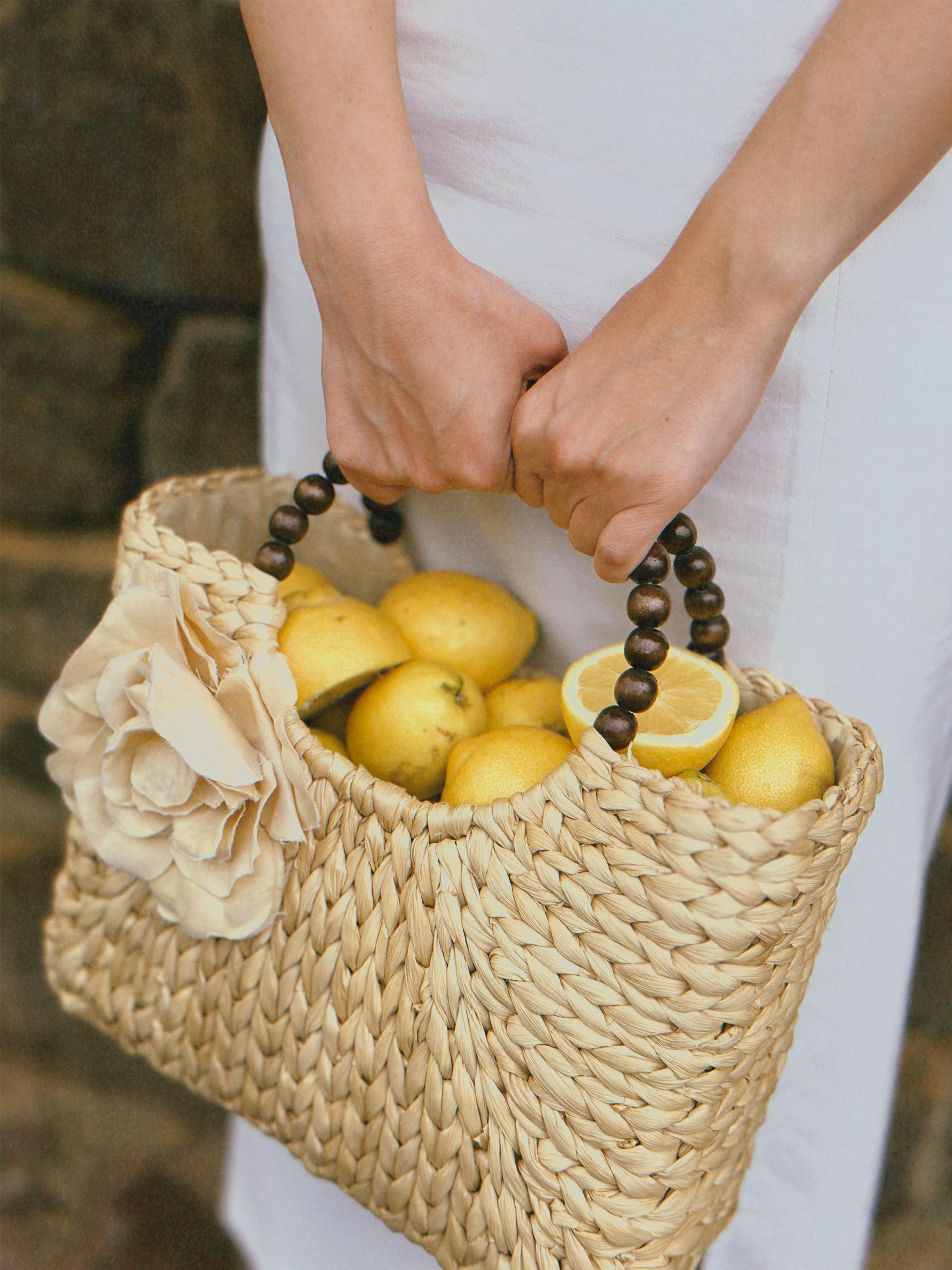 Close-up of a Woman Holding a Basket Full of Lemons 