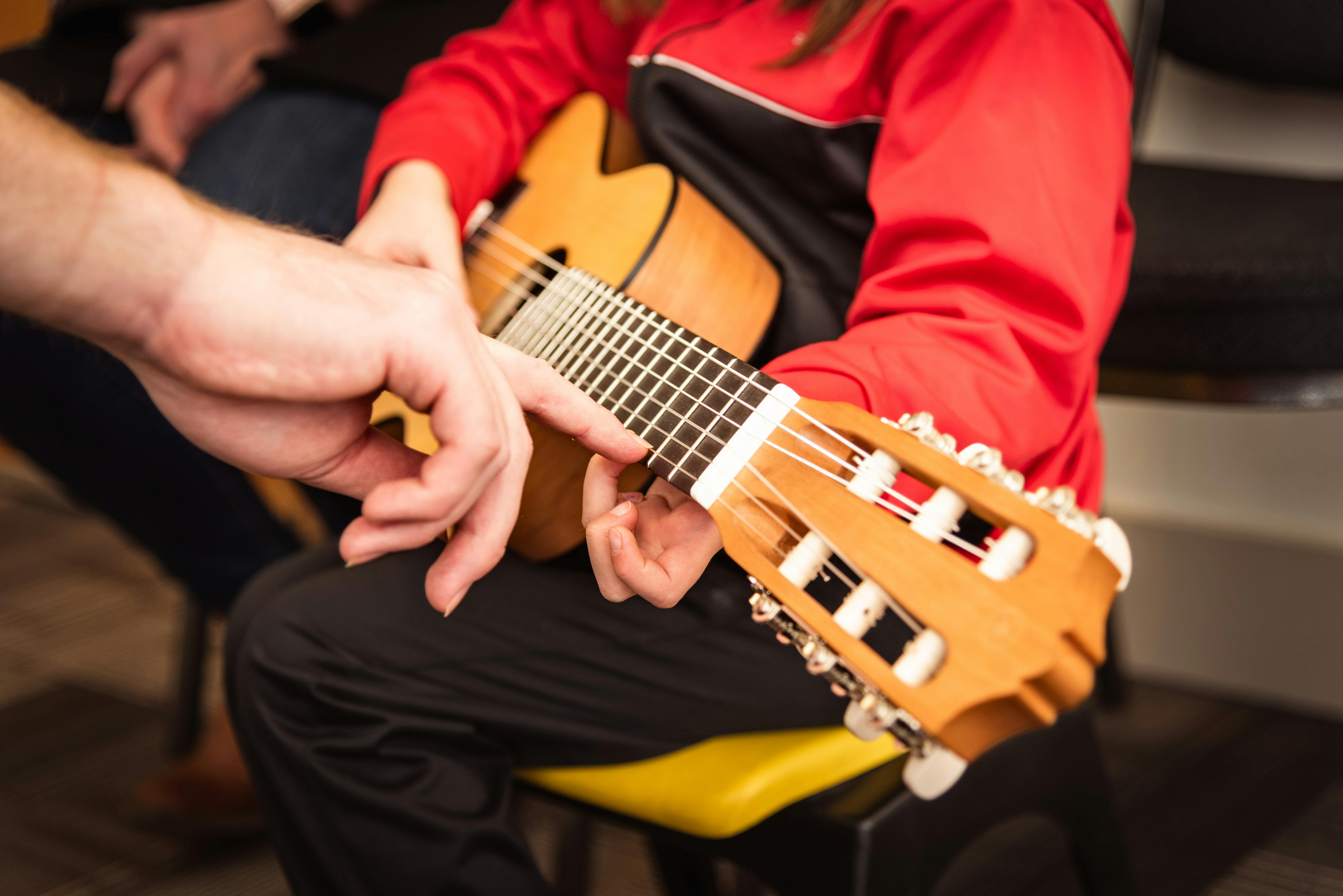 Person Teaching Child How to Play Ukulele