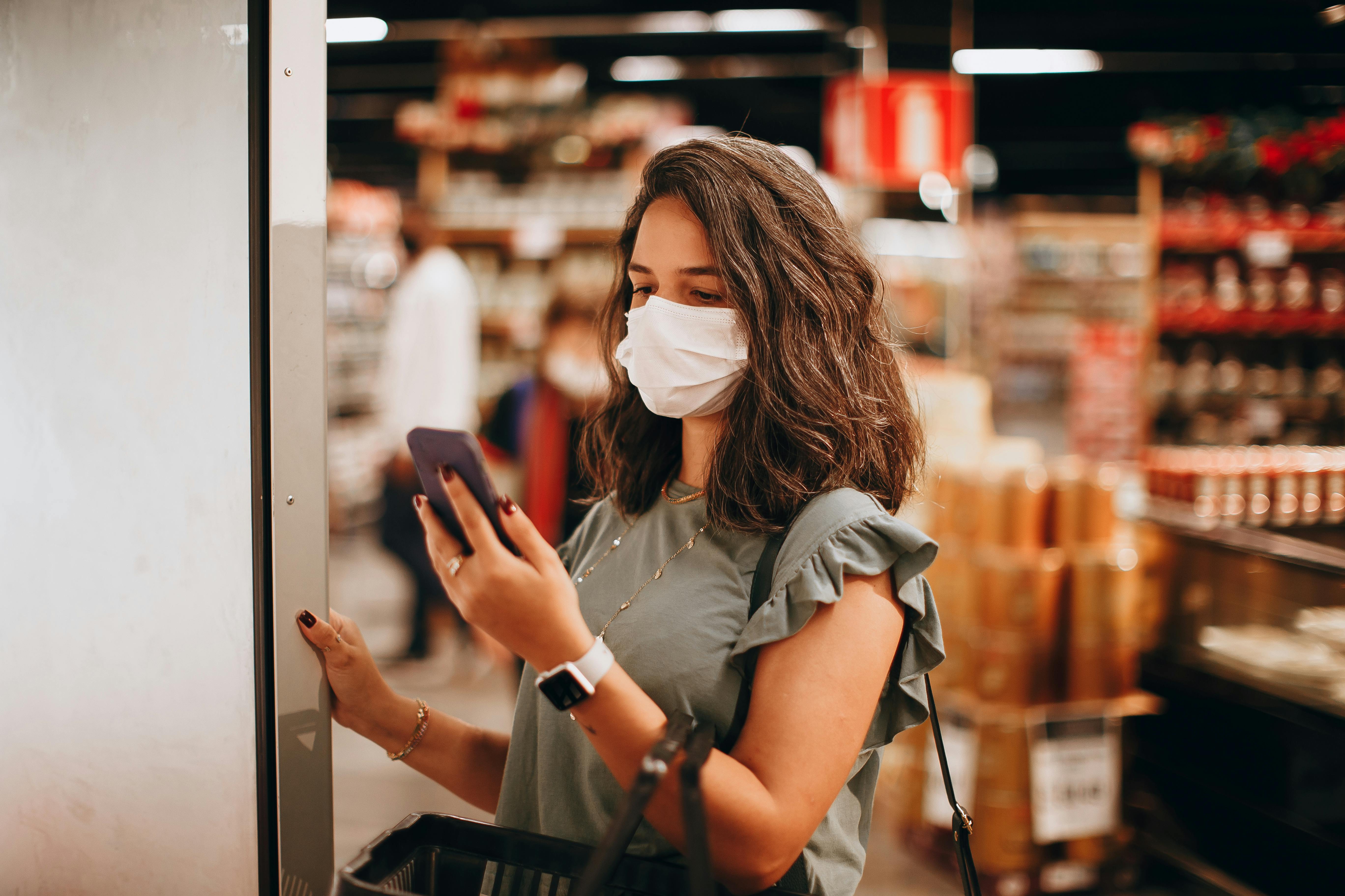 Woman in a Supermarket Looking at a Shopping List on her Smartphone