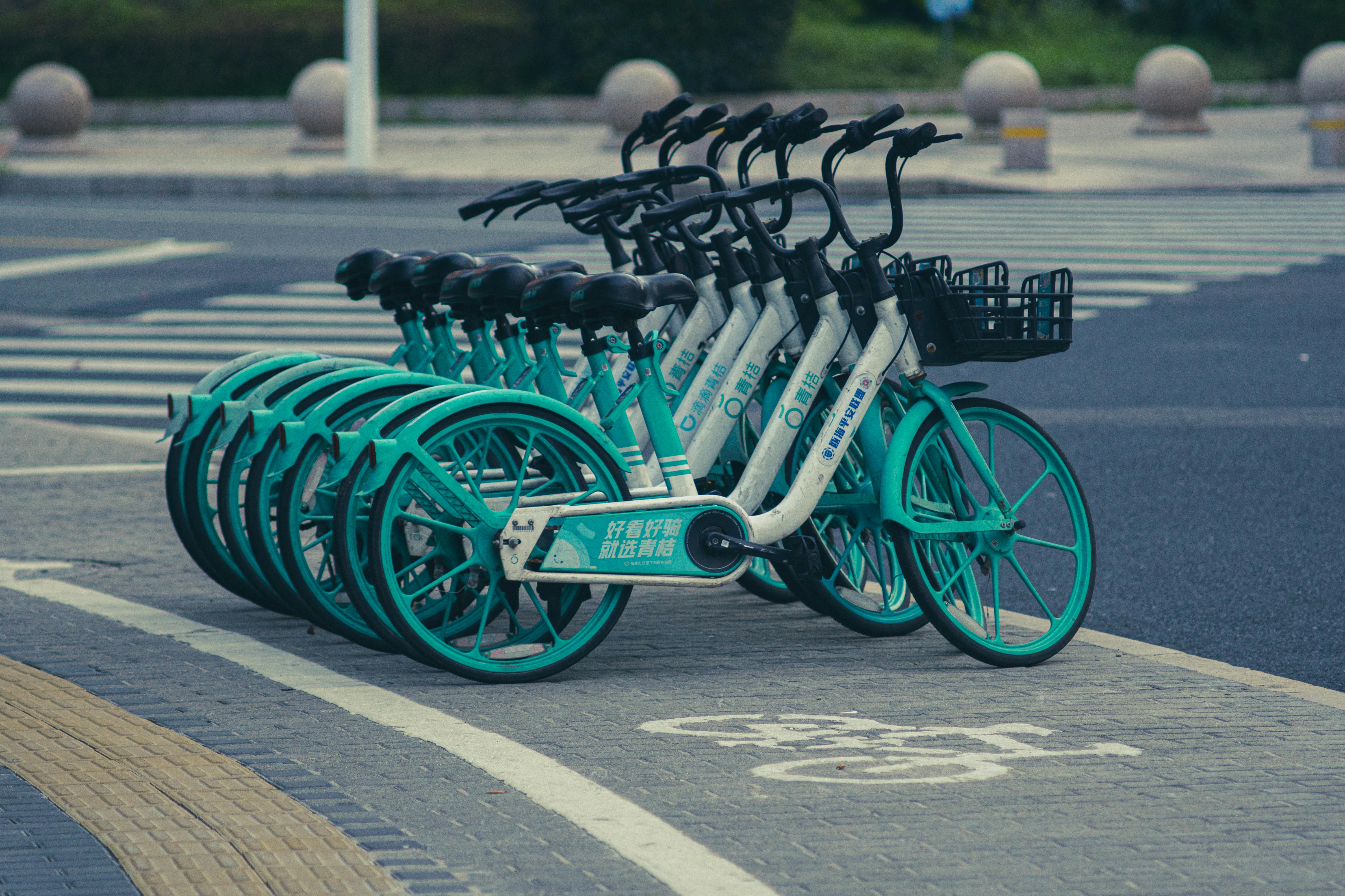 A row of green and turquoise bicycles parked on the side of the road