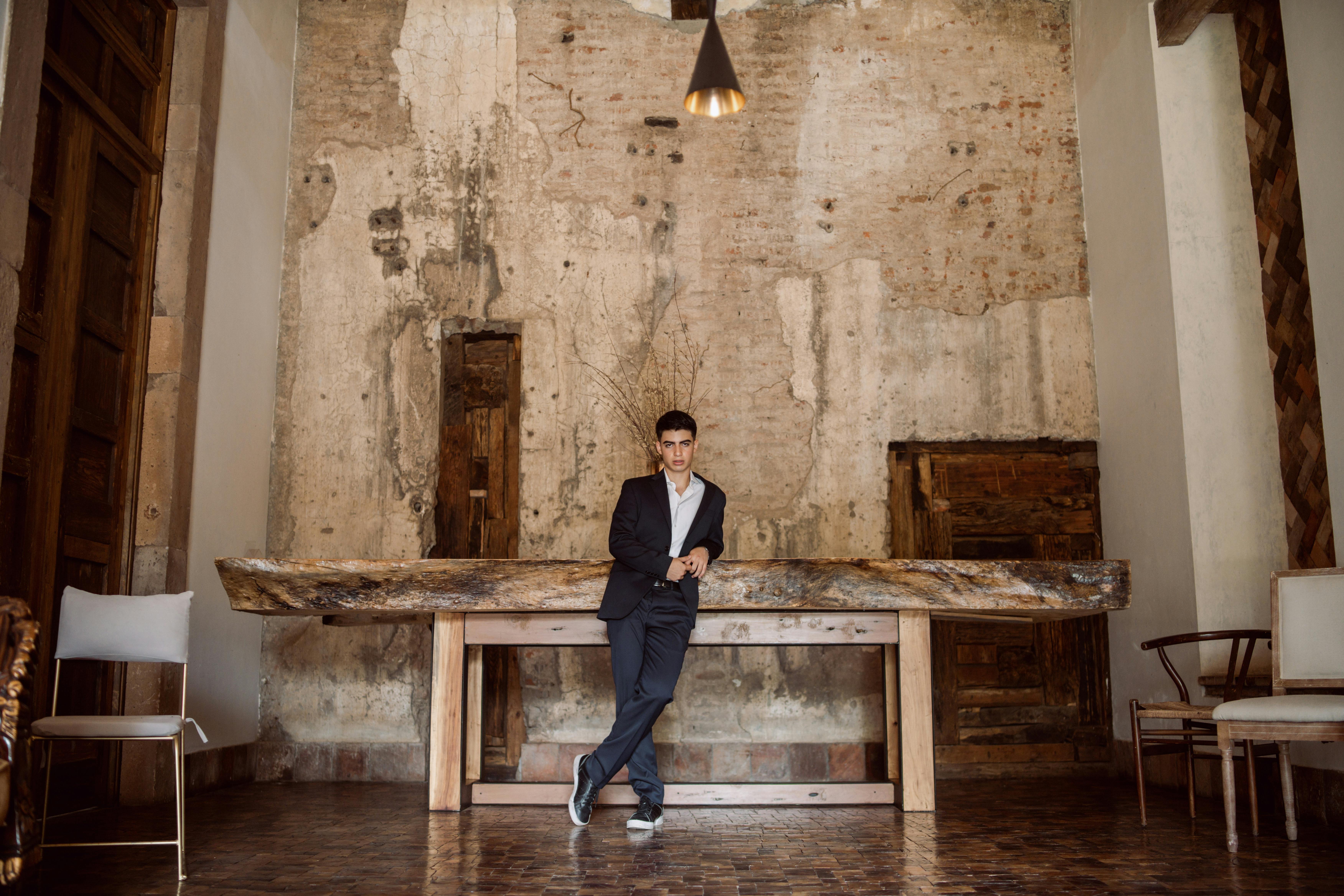 Man in Suit Leaning on Wooden Table
