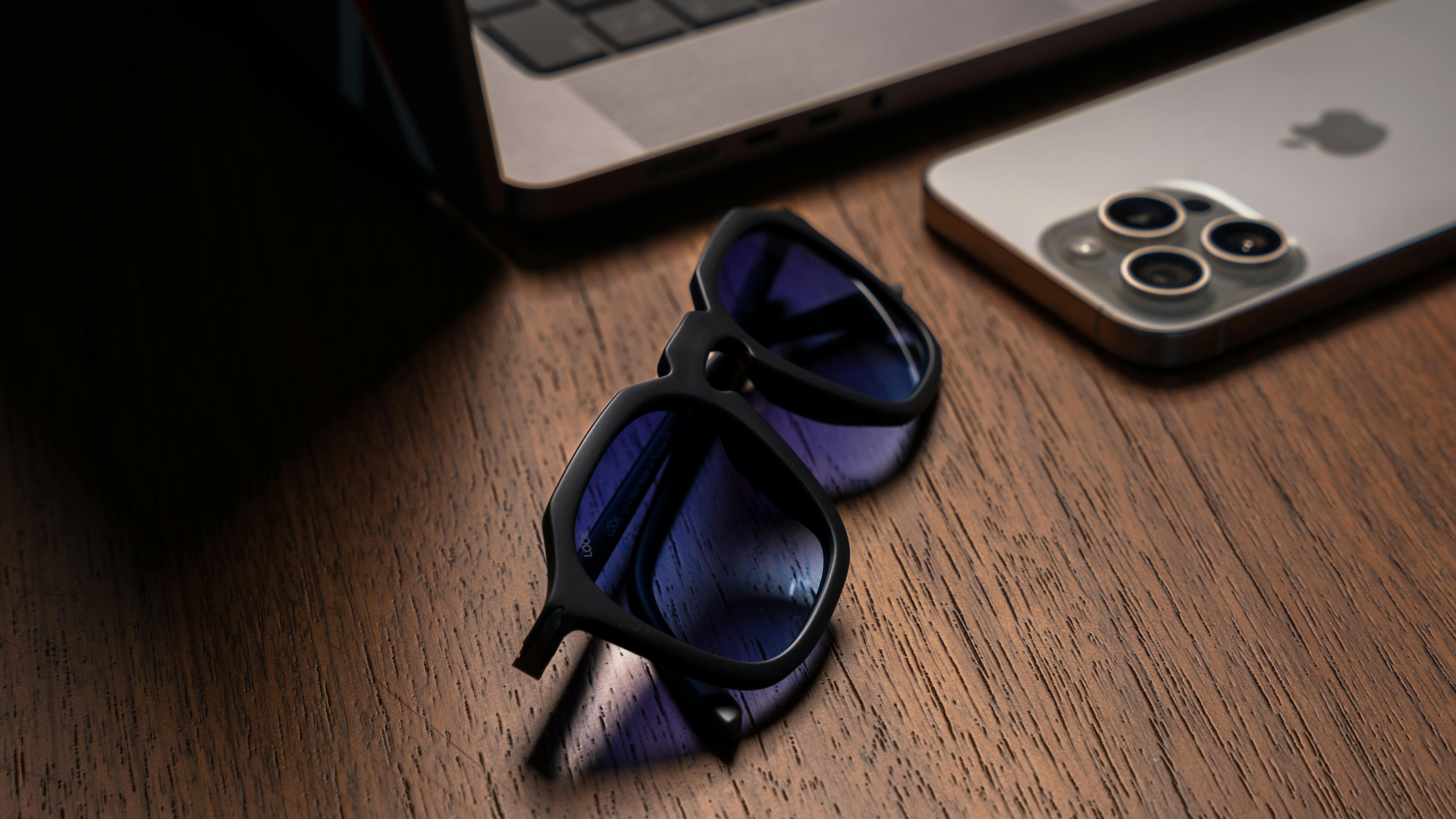 Sunglasses on the Desk Next to the Laptop and Smartphone