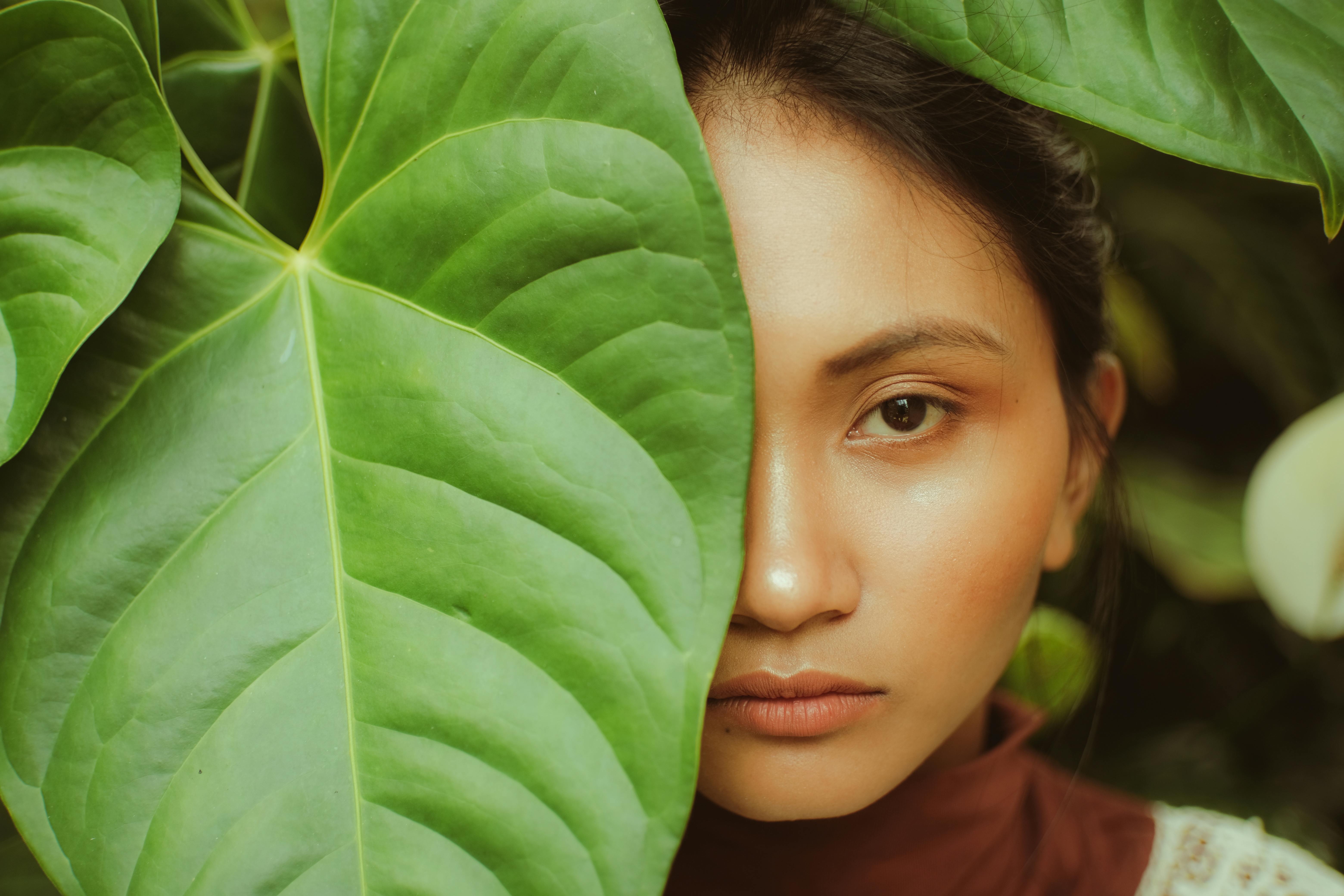 Half of the Face of a Woman Hiding Behind a Big Leaf