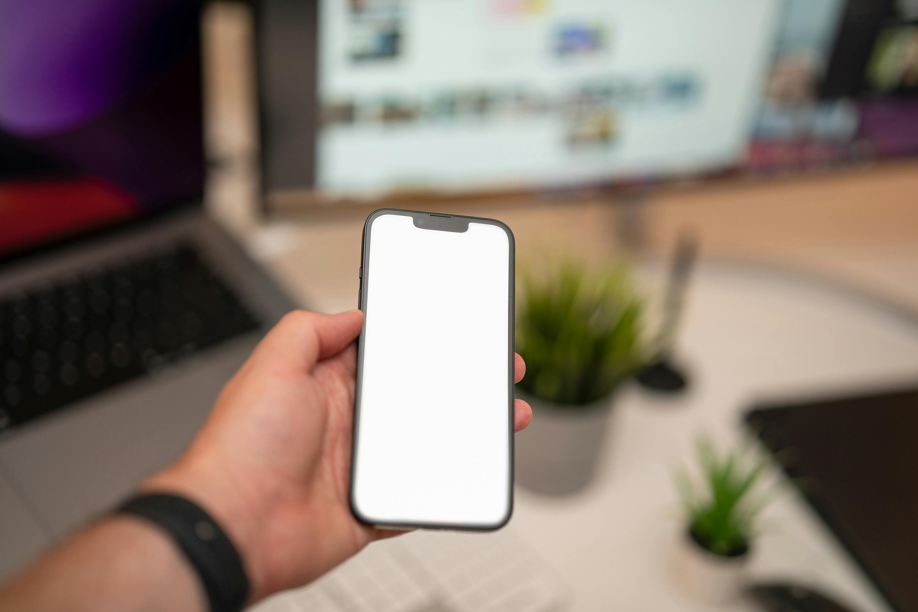 Hand holding smartphone blank screen mockup office interior.