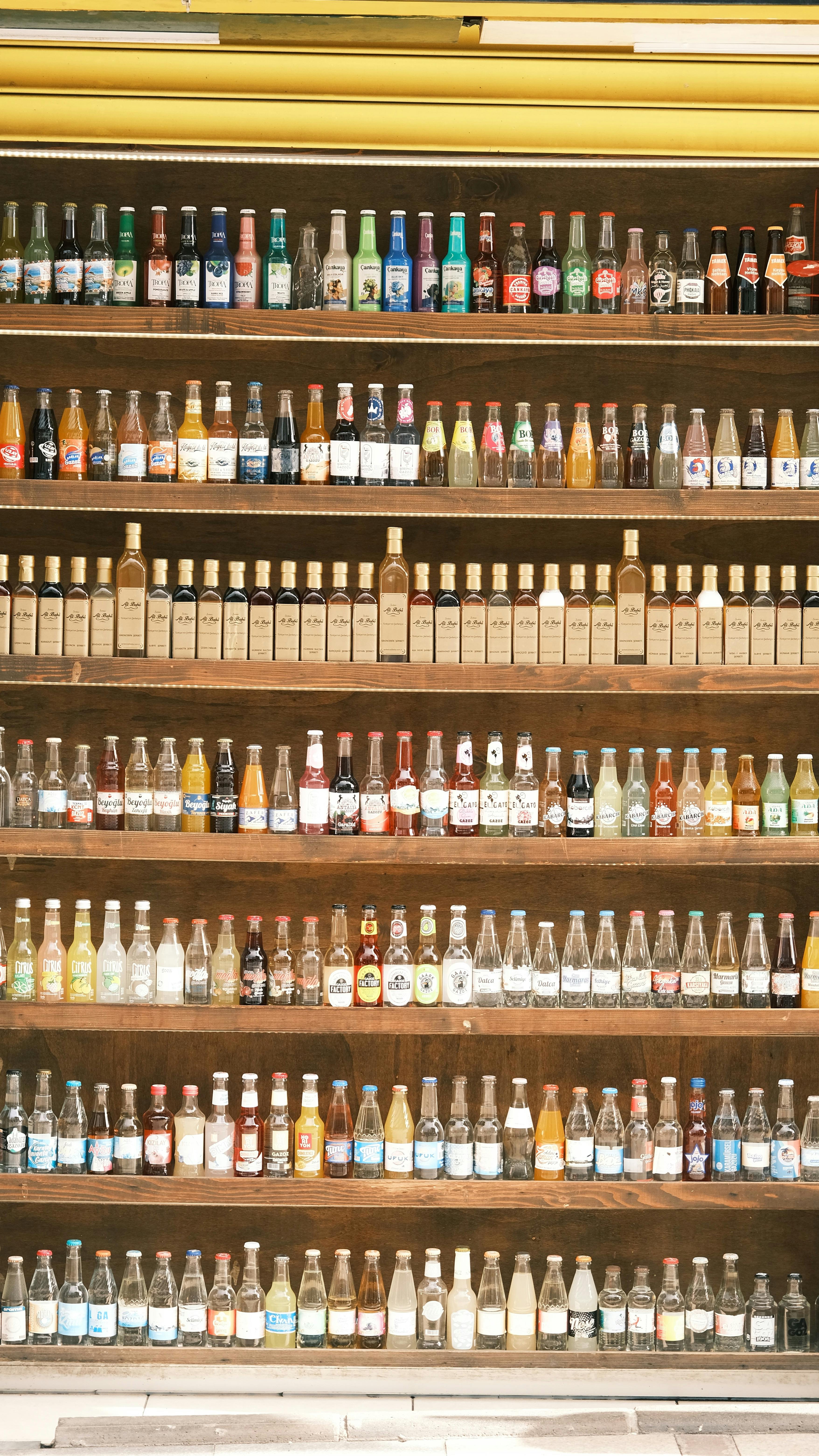 Colorful Assortment of Beverage Bottles on Wooden Shelves