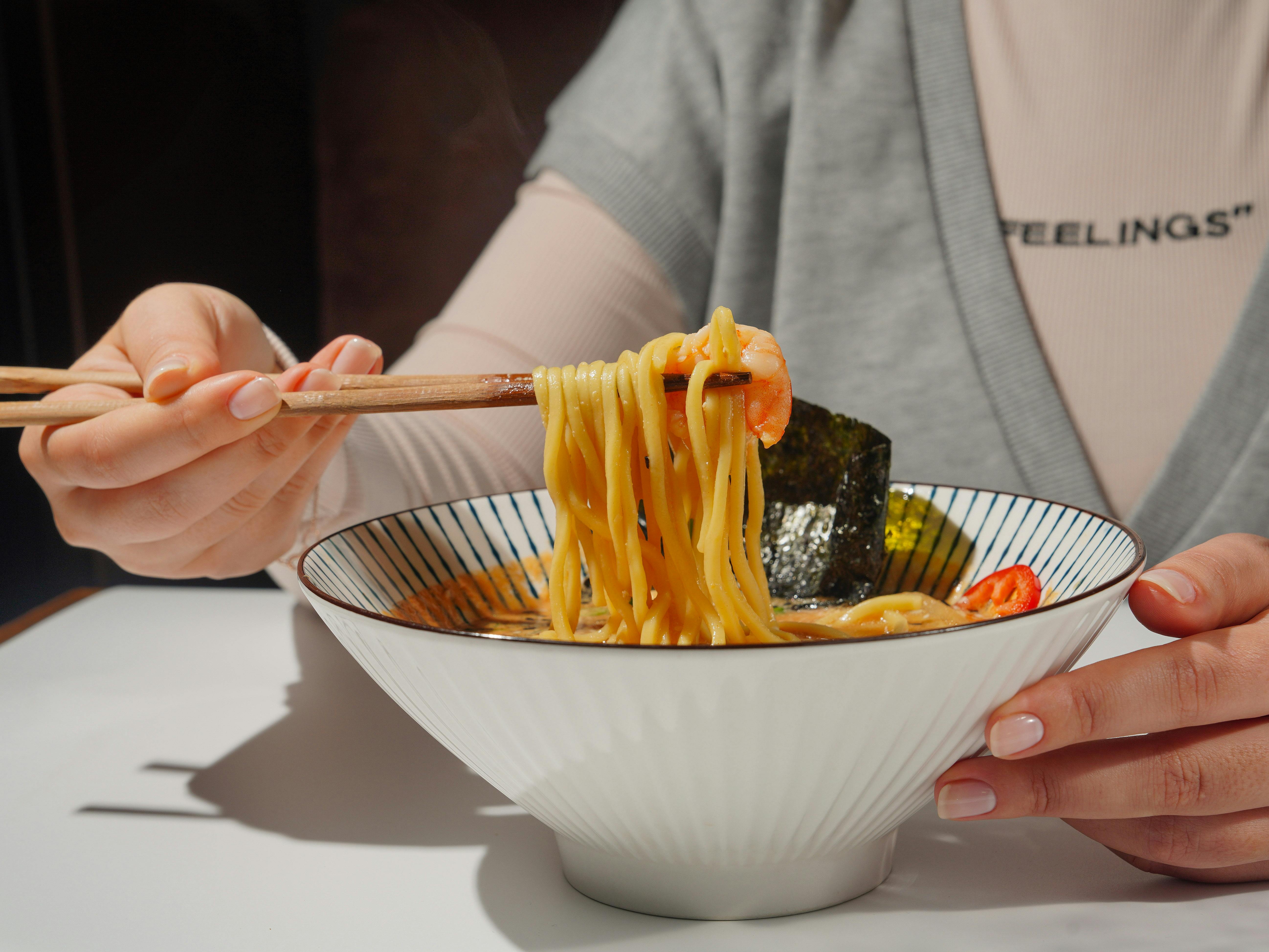 Person Enjoying Delicious Ramen with Chopsticks