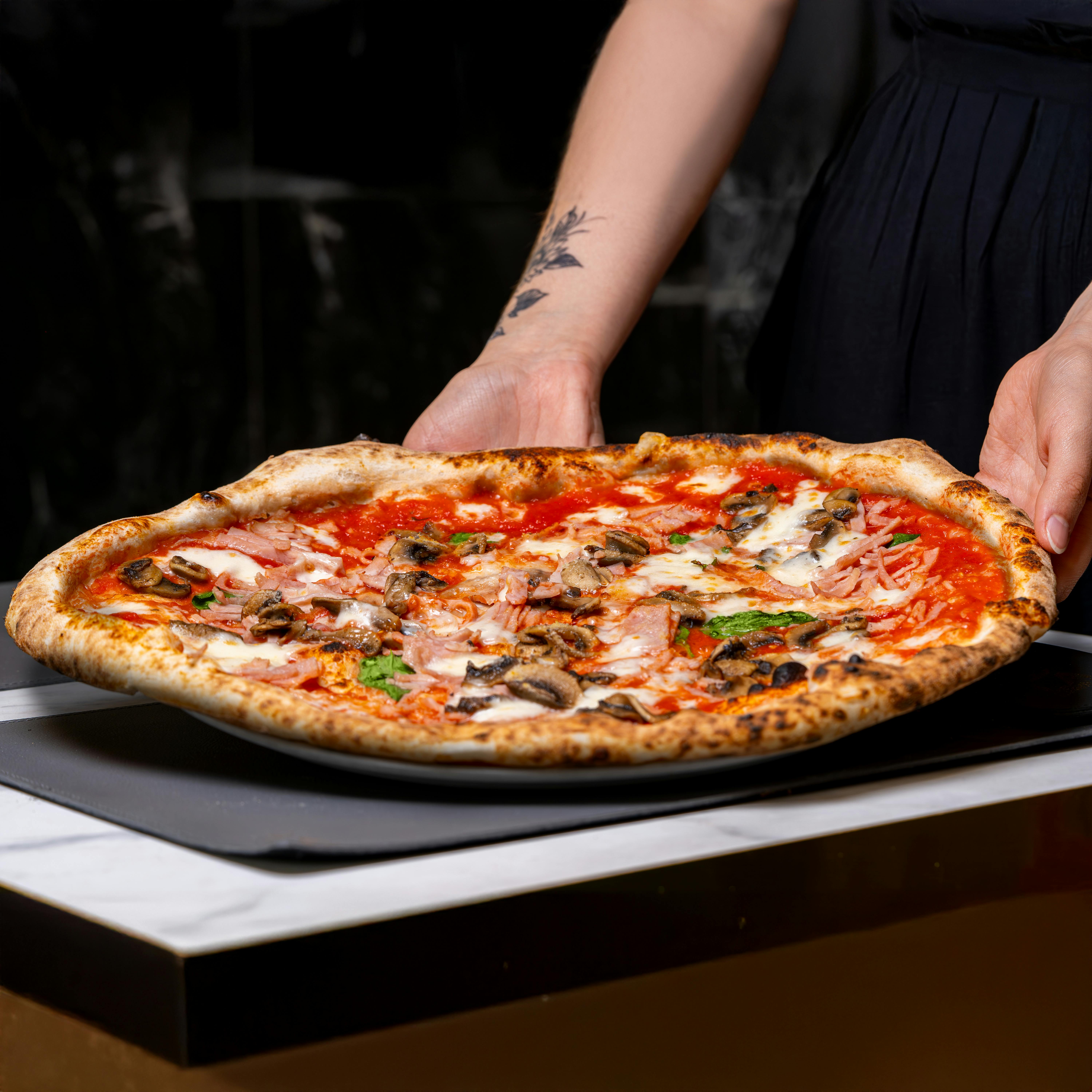 Chef serving freshly baked mushroom pizza