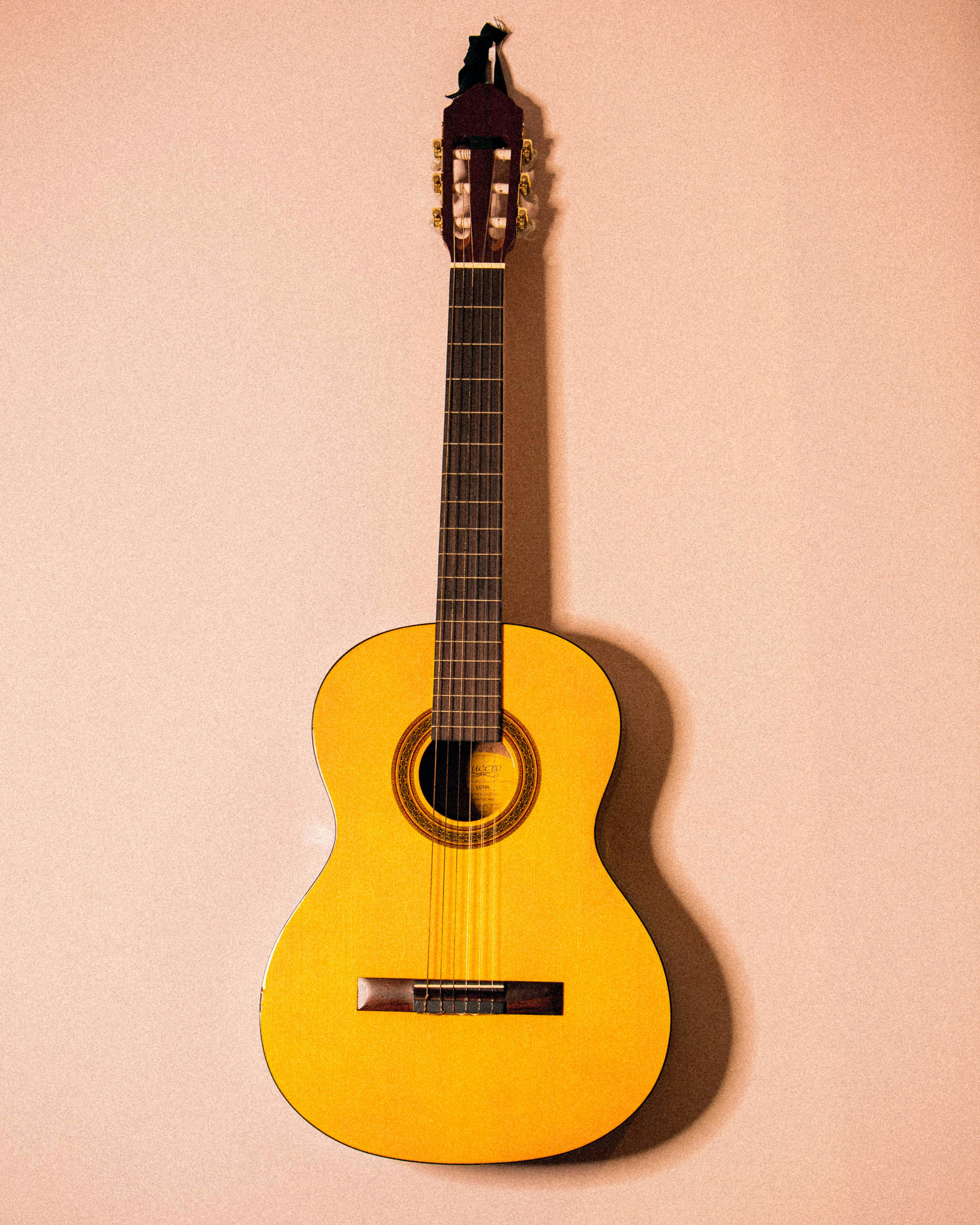 Photo Of yellow Guitar Hanged On Pink Wall